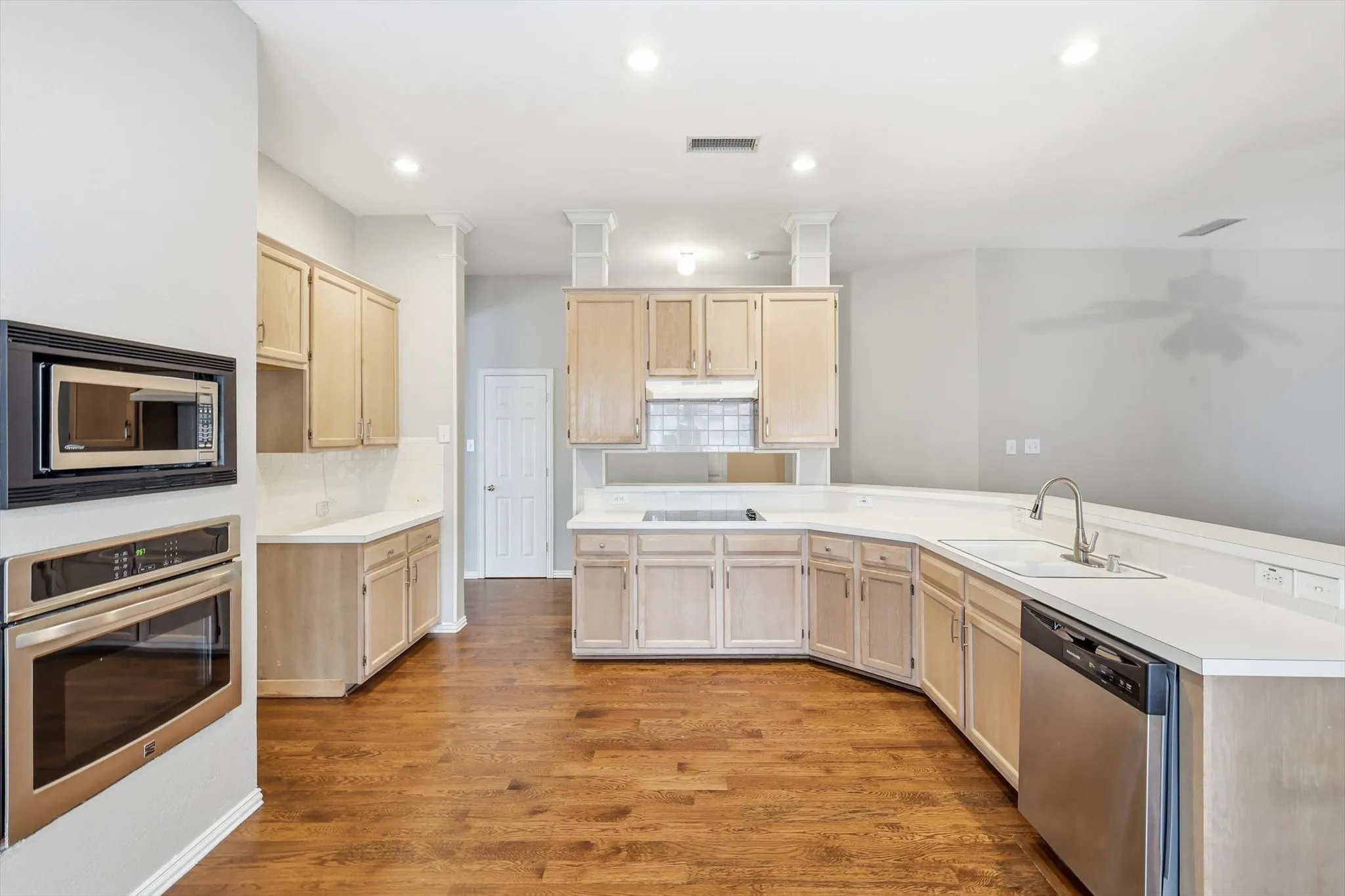 Kitchen featuring wood-finish flooring, light-toned cabinetry, stainless steel appliances, white countertops, and recessed lighting