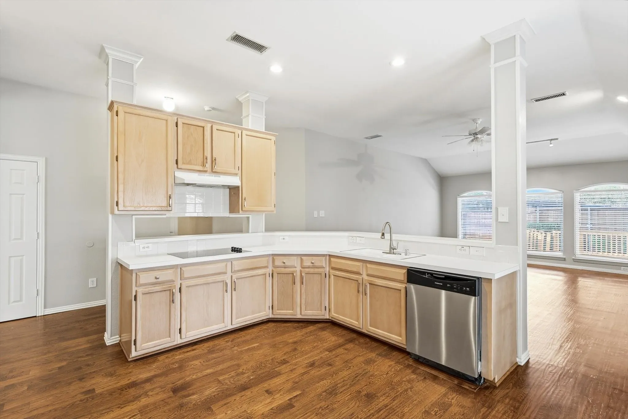 U-shaped kitchen featuring light wood cabinetry, white countertops, stainless steel dishwasher, and a built-in cooktop