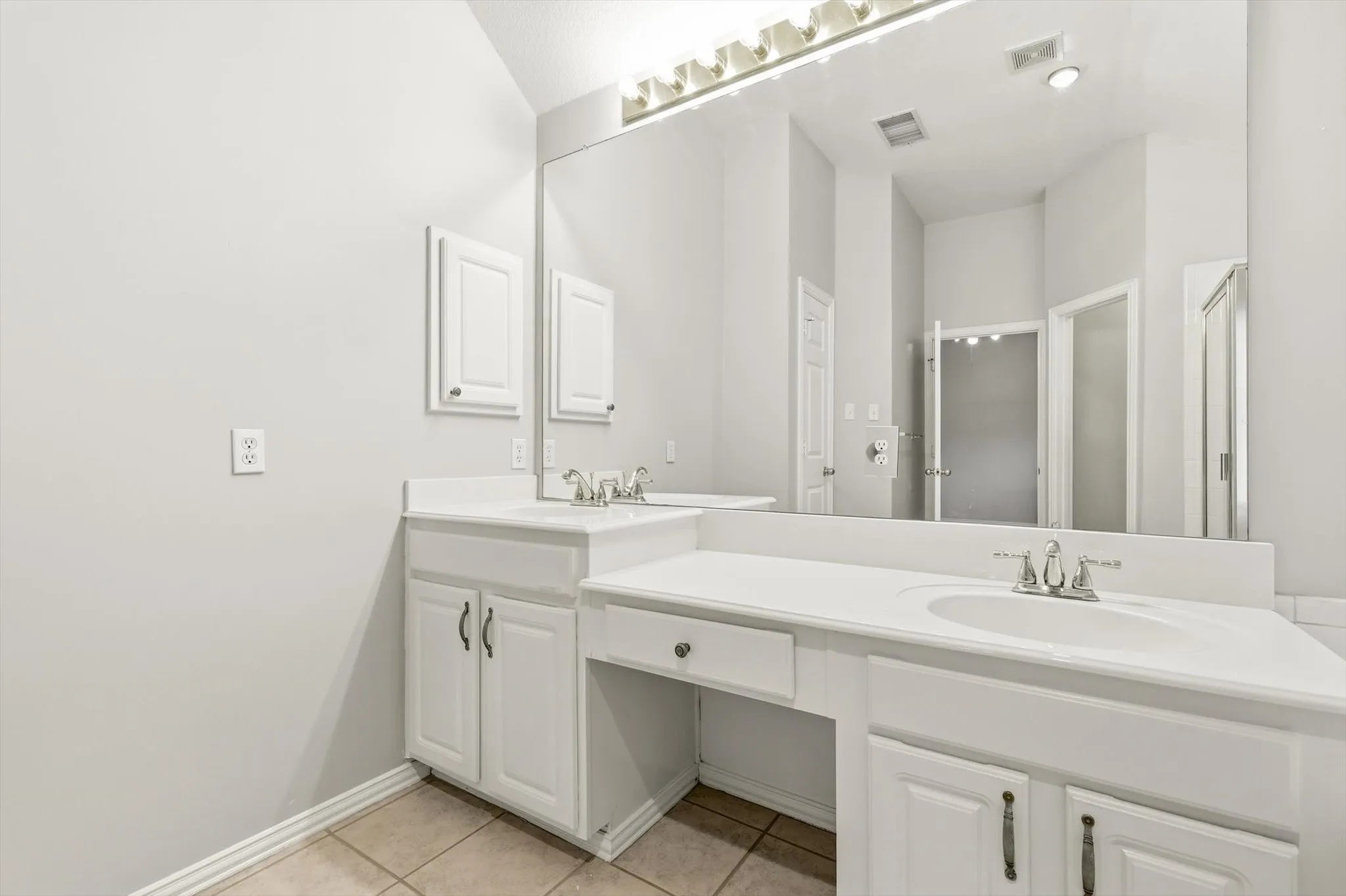 Double vanity with integrated sinks, white cabinetry, and a dedicated vanity area