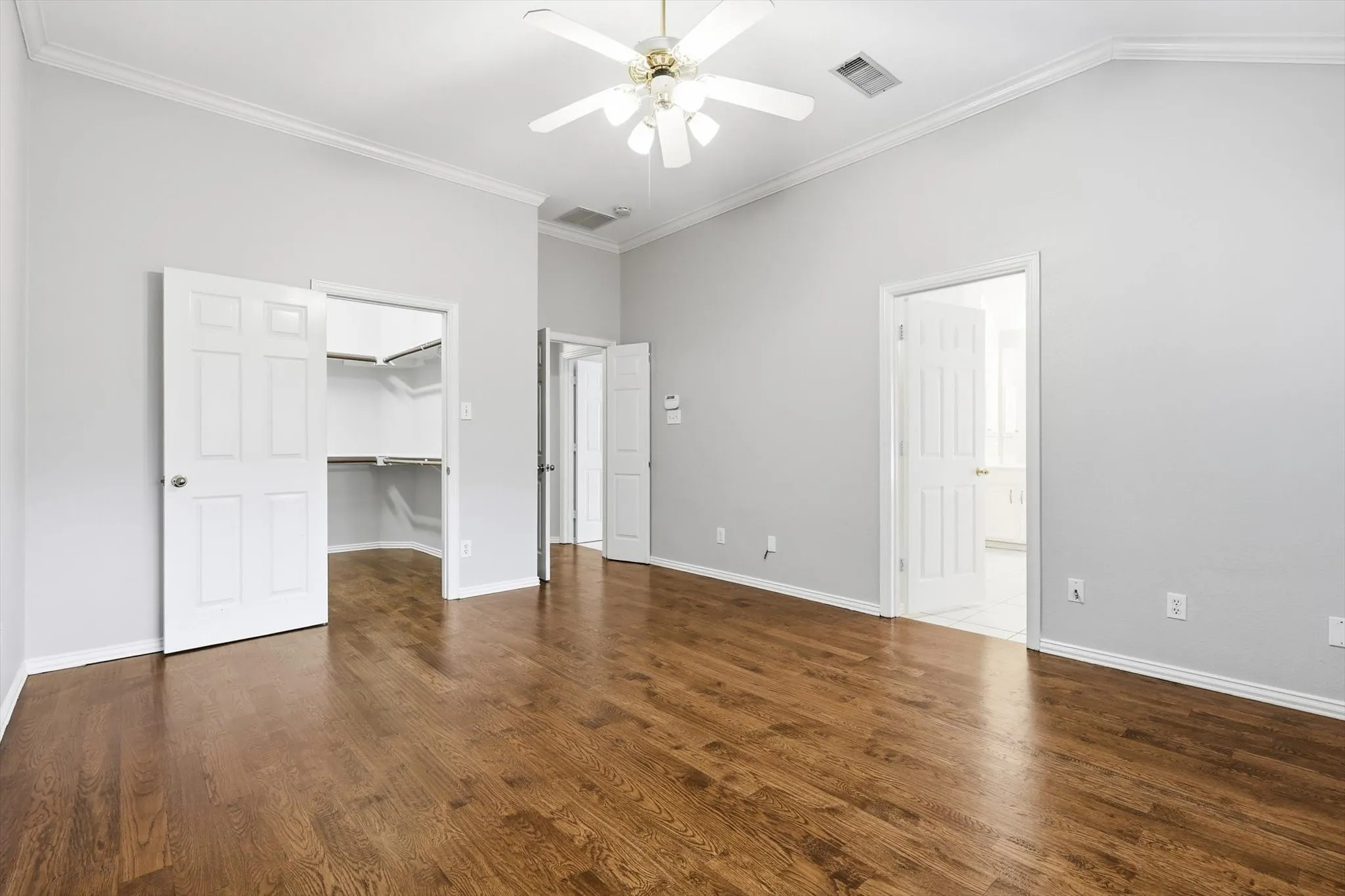 Spacious room featuring wood-finish flooring, vaulted ceilings, and a ceiling fan