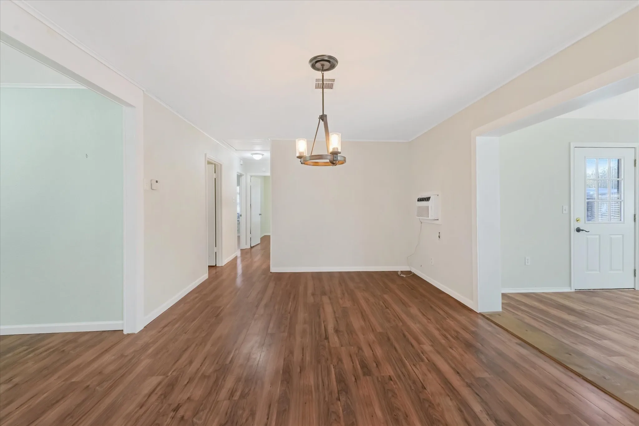 Unfurnished dining area featuring dark wood-style floors, a chandelier, and ornamental molding