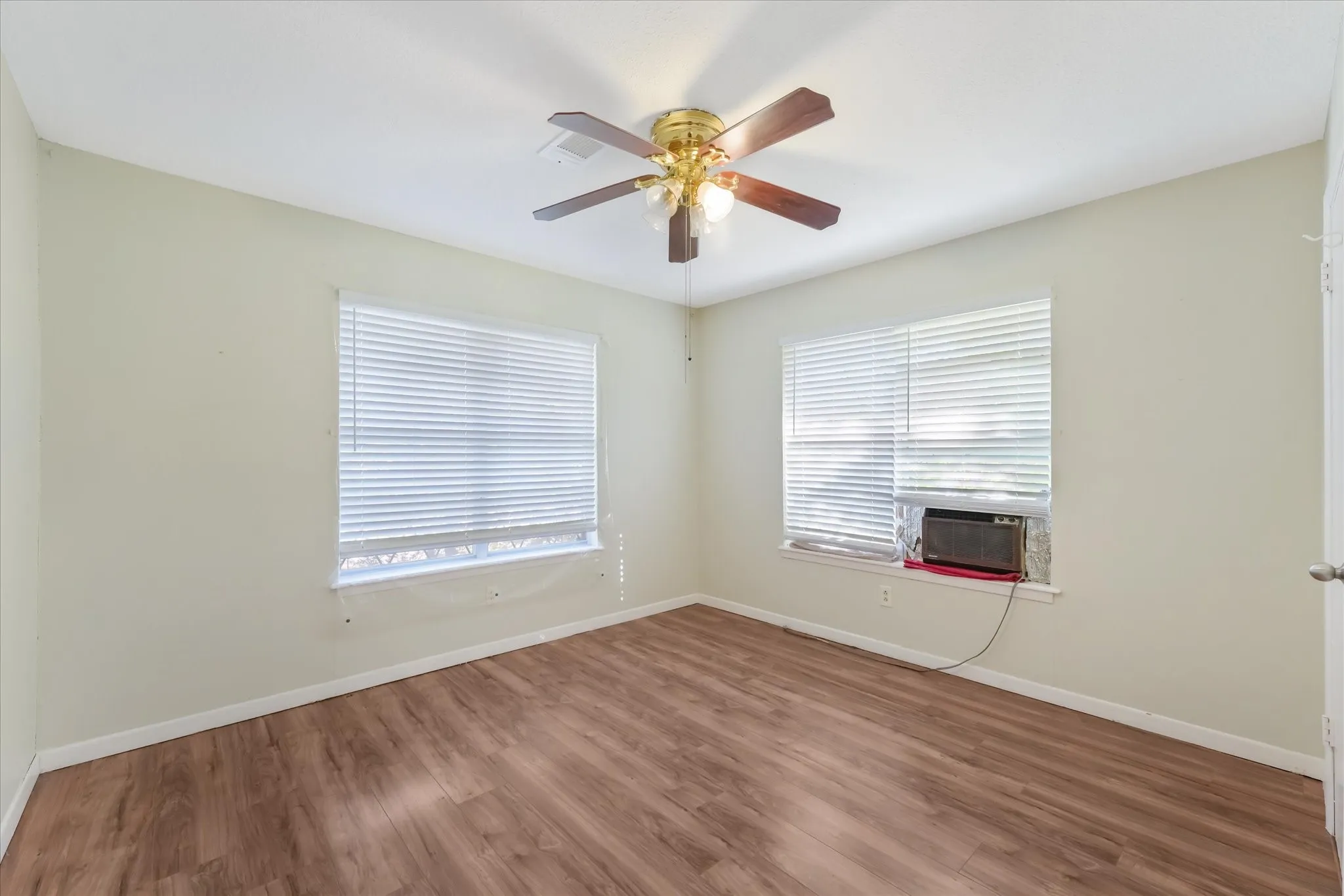 Spare room featuring wood finished floors, healthy amount of natural light, ceiling fan, and cooling unit