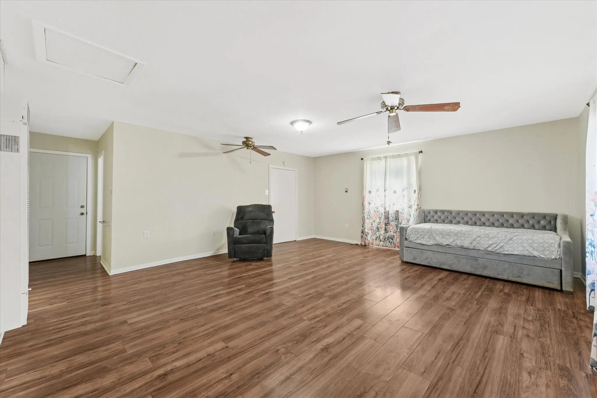 Unfurnished room with dark wood-style floors, attic access, and ceiling fan