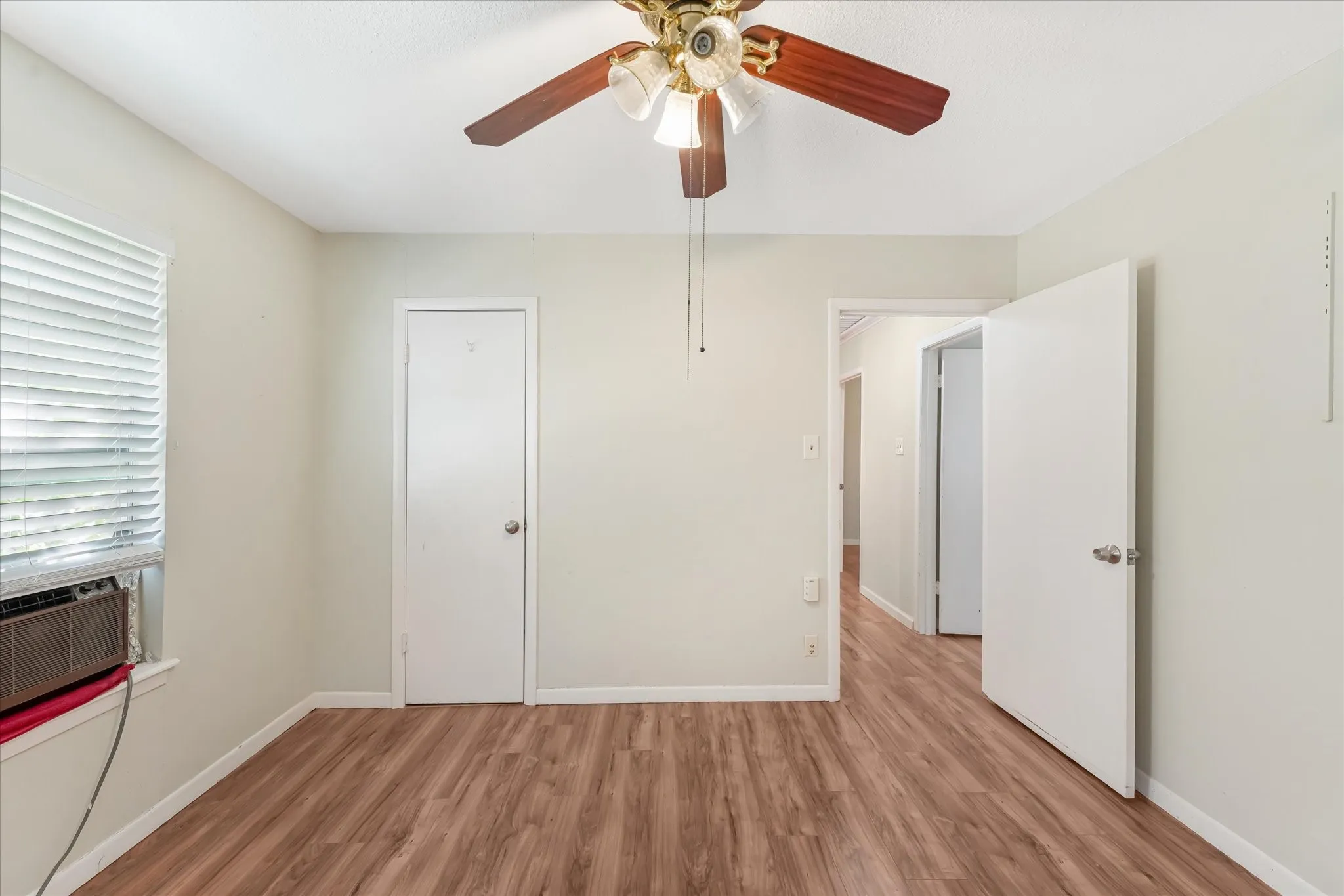 Unfurnished bedroom with light wood-style flooring, a ceiling fan, and cooling unit