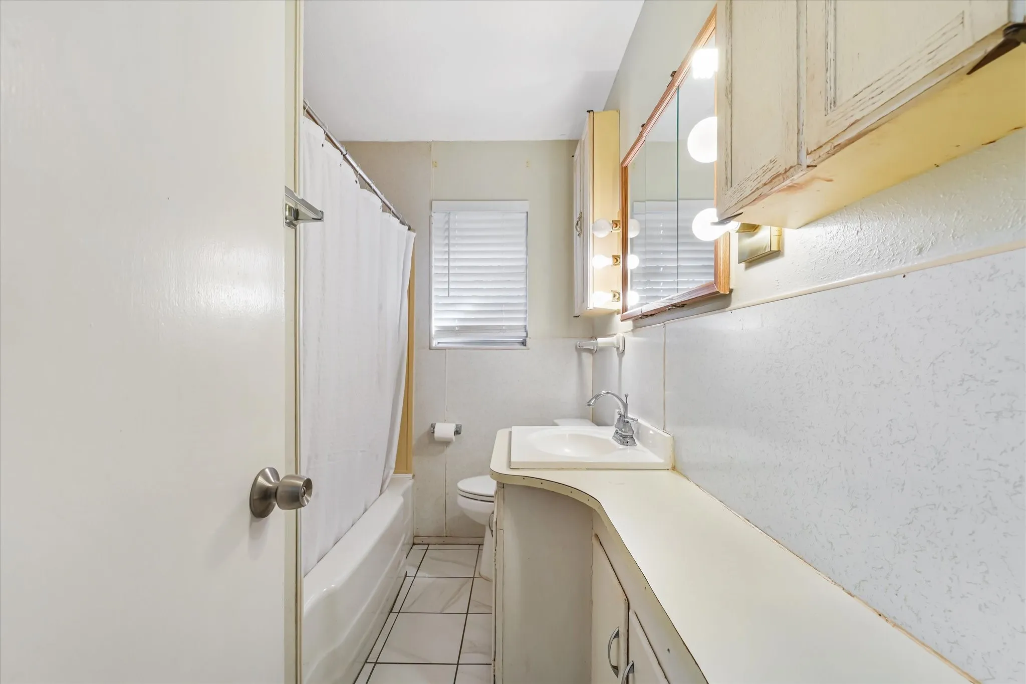 Full bath featuring vanity, shower / bath combo, and light tile patterned flooring