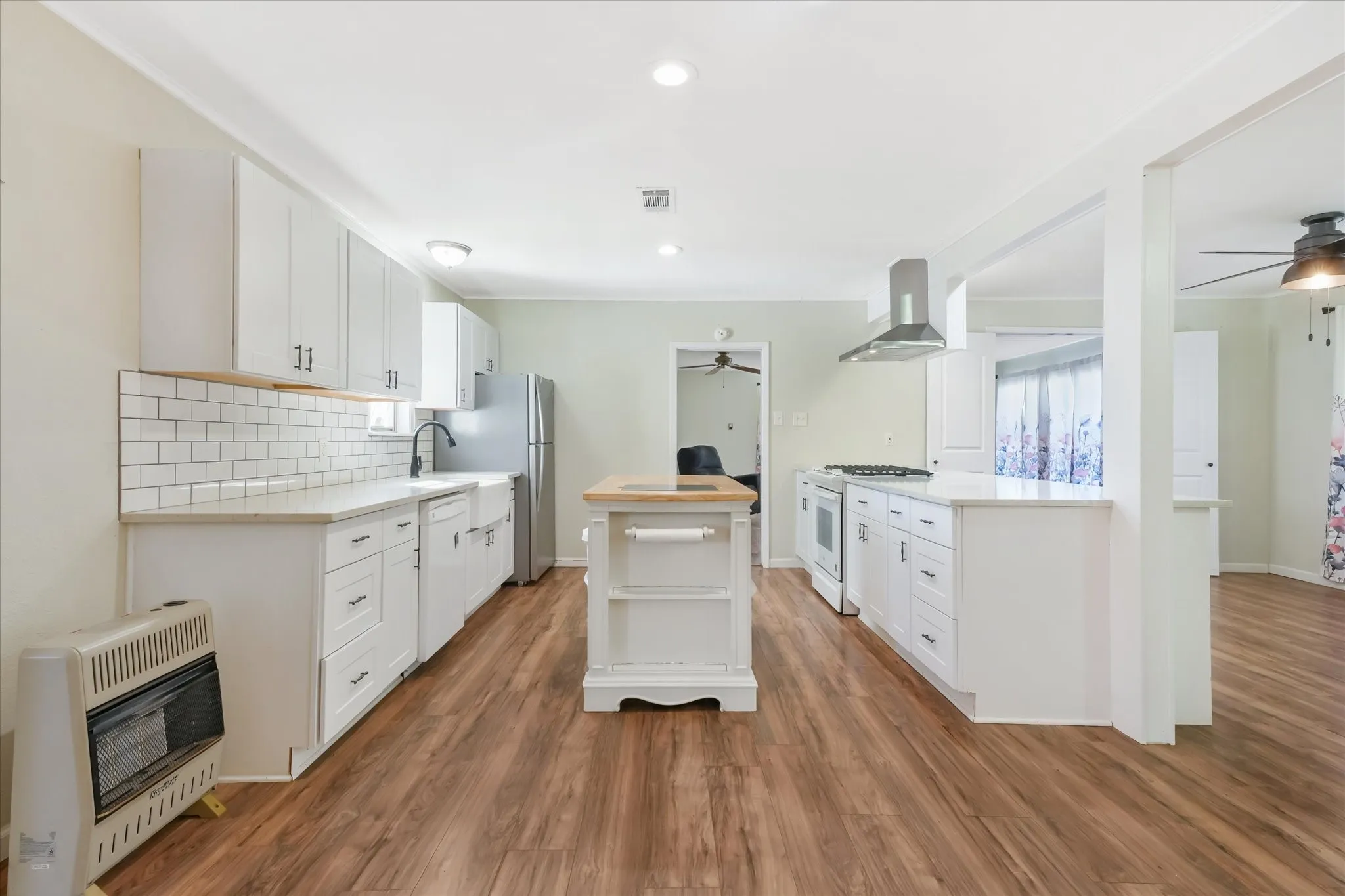 Kitchen with heating unit, a ceiling fan, white cabinetry, recessed lighting, and light wood-style floors