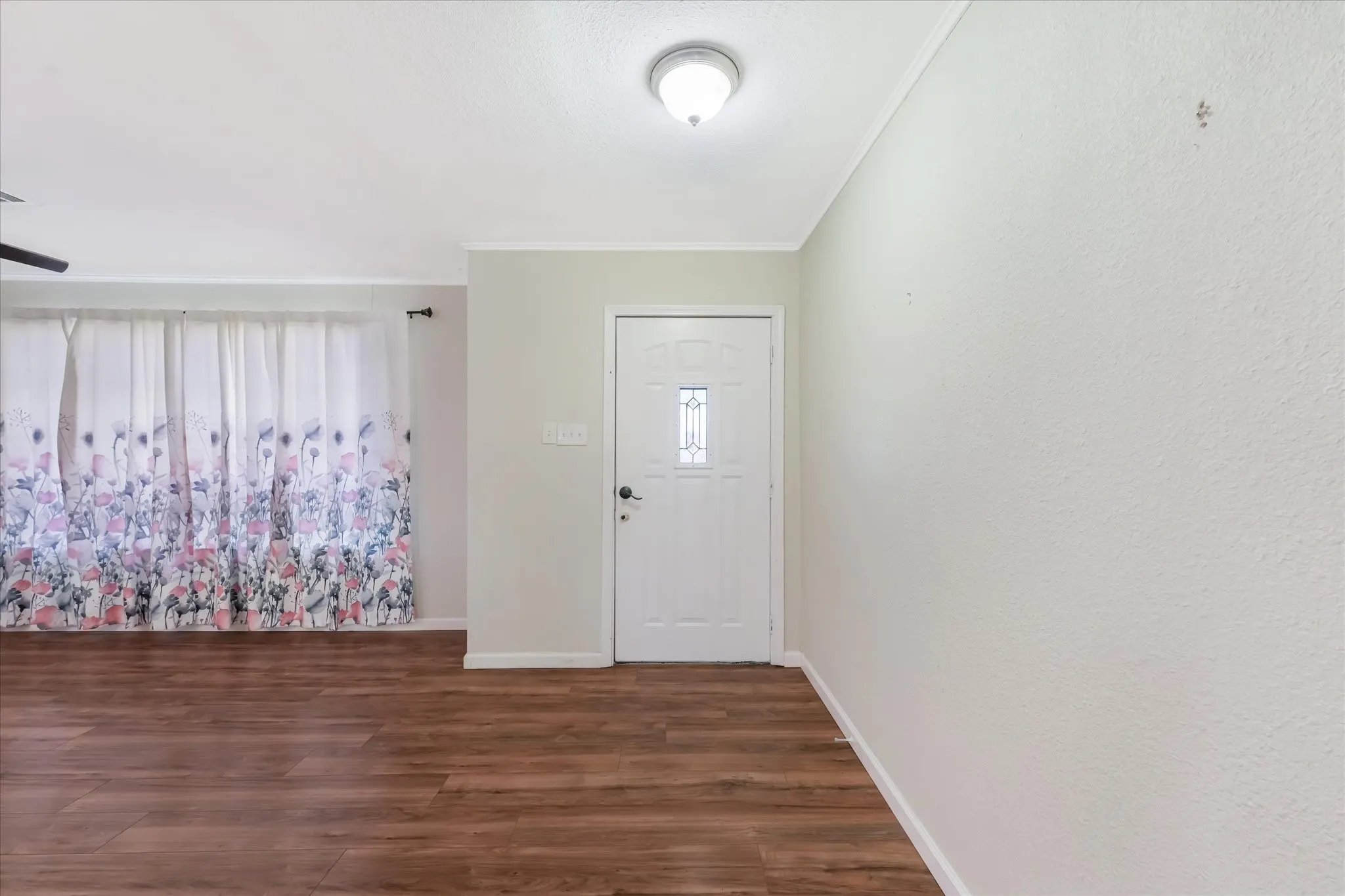 Foyer with dark wood-type flooring and crown molding