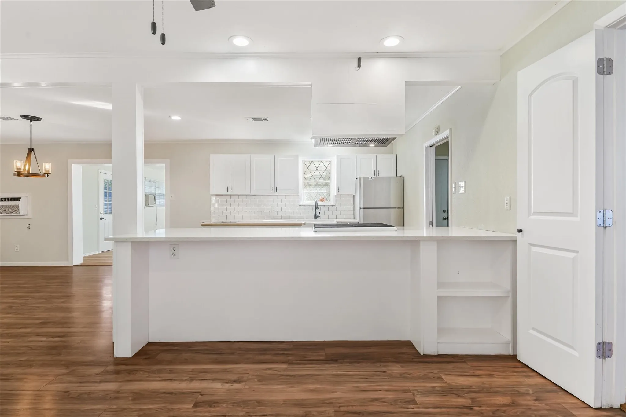 Kitchen featuring crown molding, white cabinets, dark wood finished floors, tasteful backsplash, and freestanding refrigerator