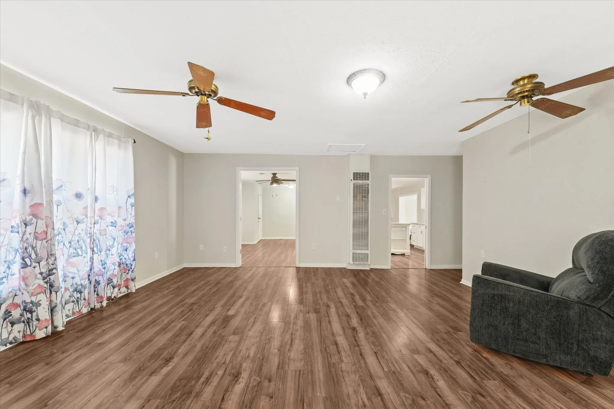 Unfurnished living room featuring dark wood-style floors, ceiling fan, a heating unit, and attic access