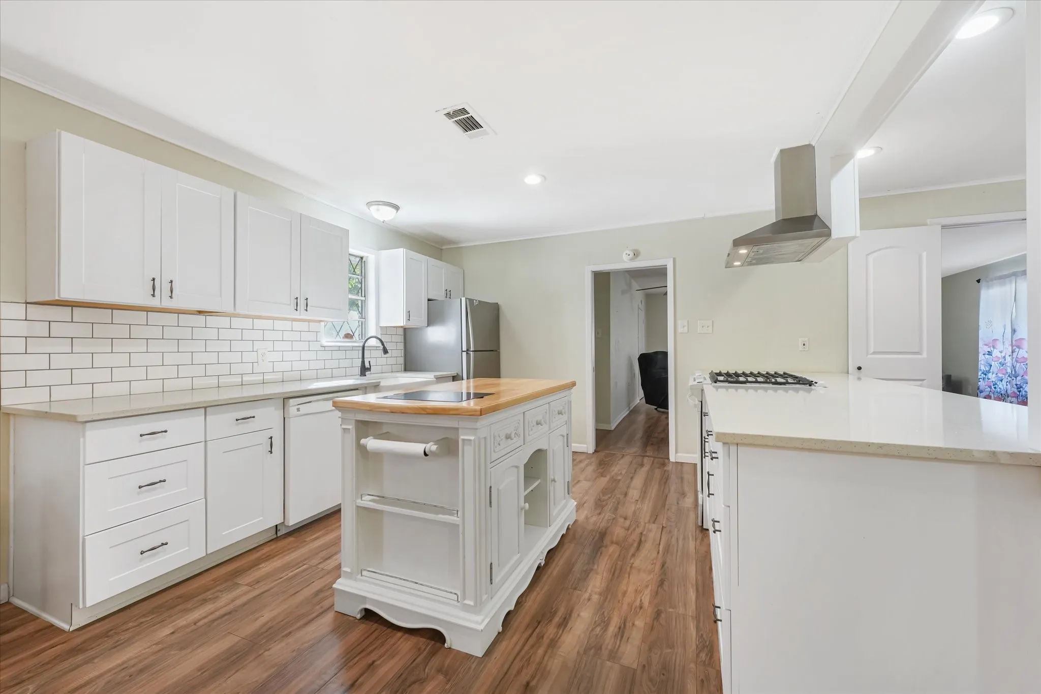 Kitchen with light stone counters, white cabinets, dark wood-type flooring, a kitchen island, and recessed lighting