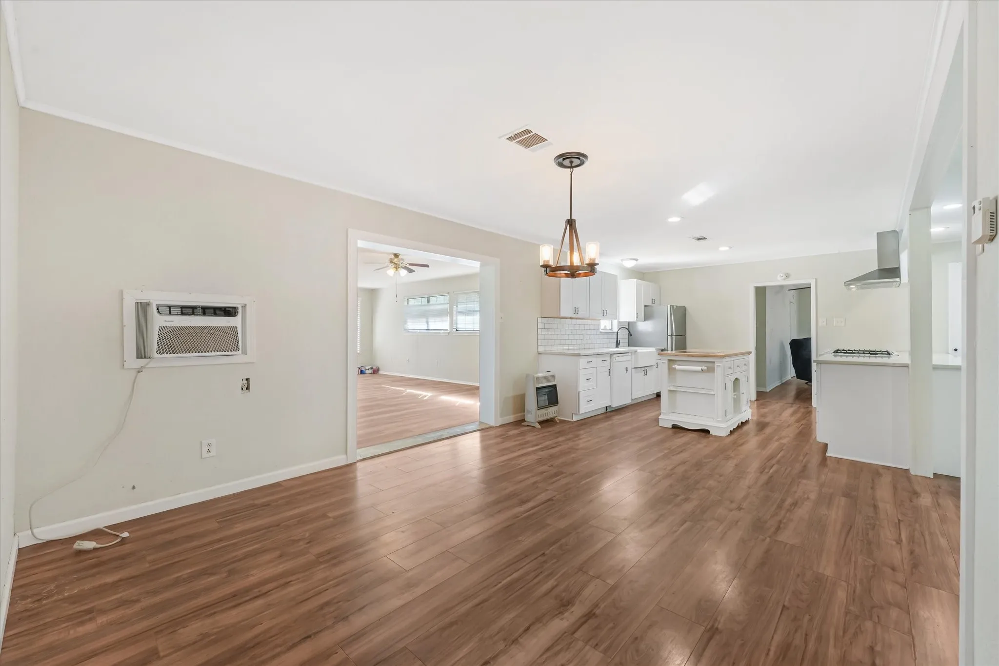 Unfurnished living room featuring dark wood-type flooring, a chandelier, heating unit, a wall mounted AC, and recessed lighting