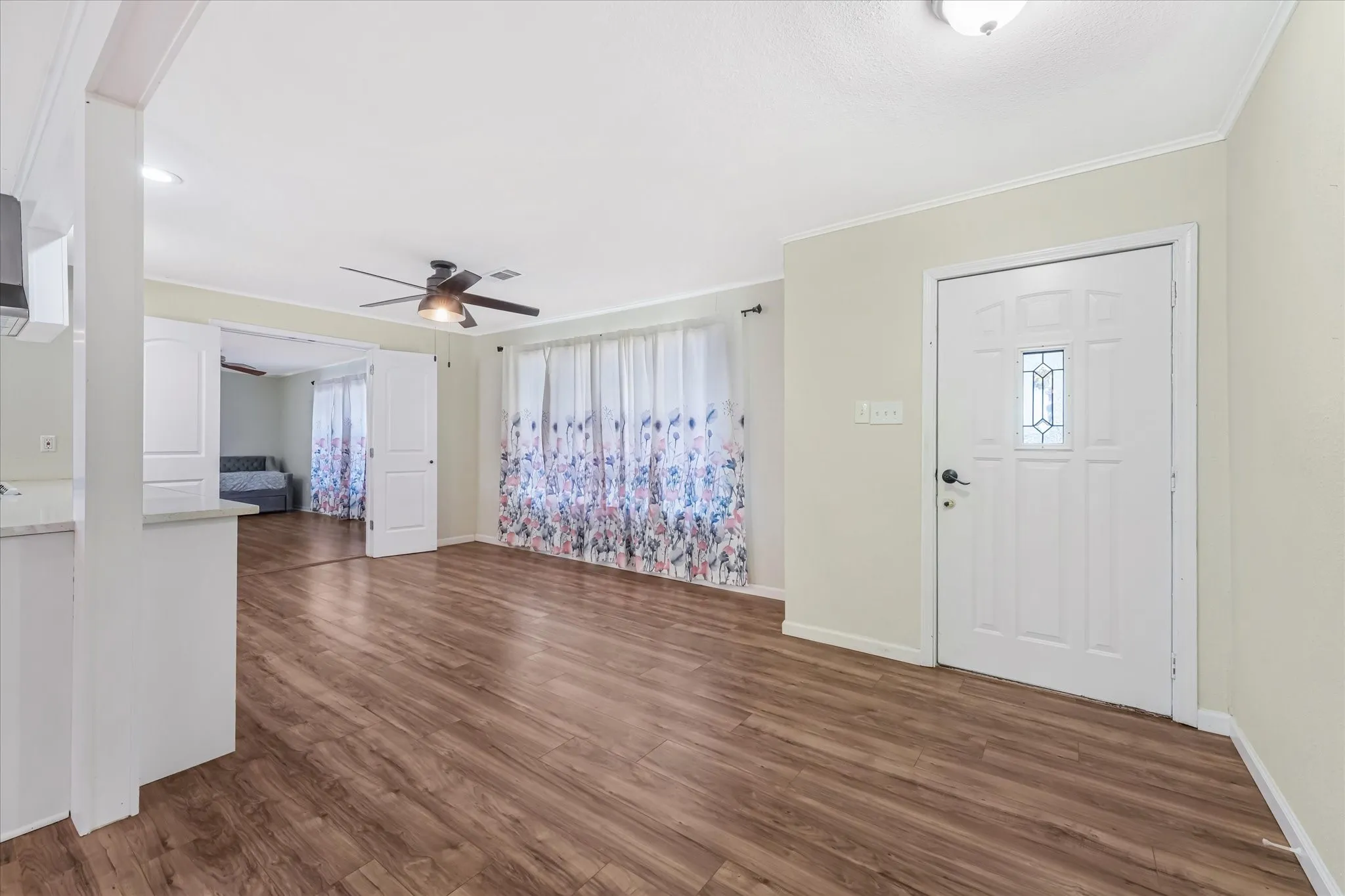 Entrance foyer with dark wood finished floors, ornamental molding, healthy amount of natural light, and a ceiling fan