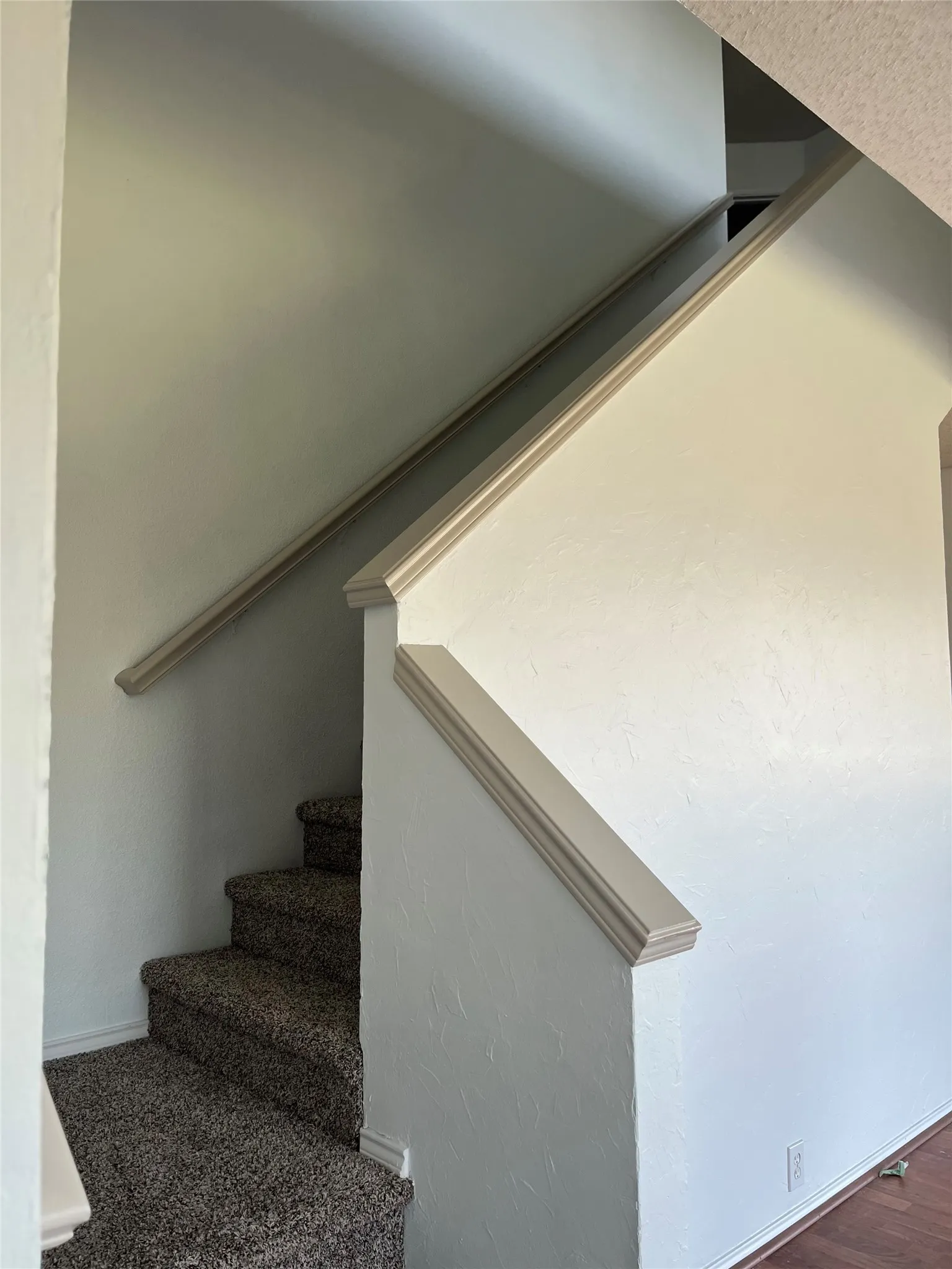 Carpeted stairway featuring a half-wall with decorative trim and a handrail