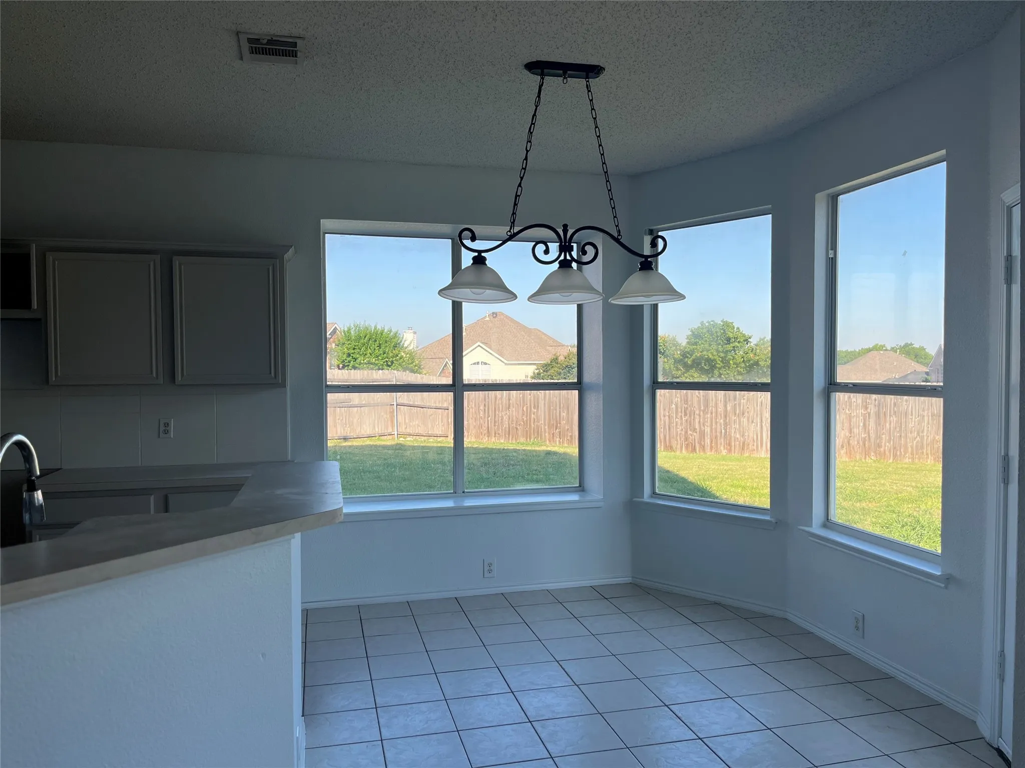 Breakfast nook with bay windows, ceramic tile flooring, and a wrought iron chandelier