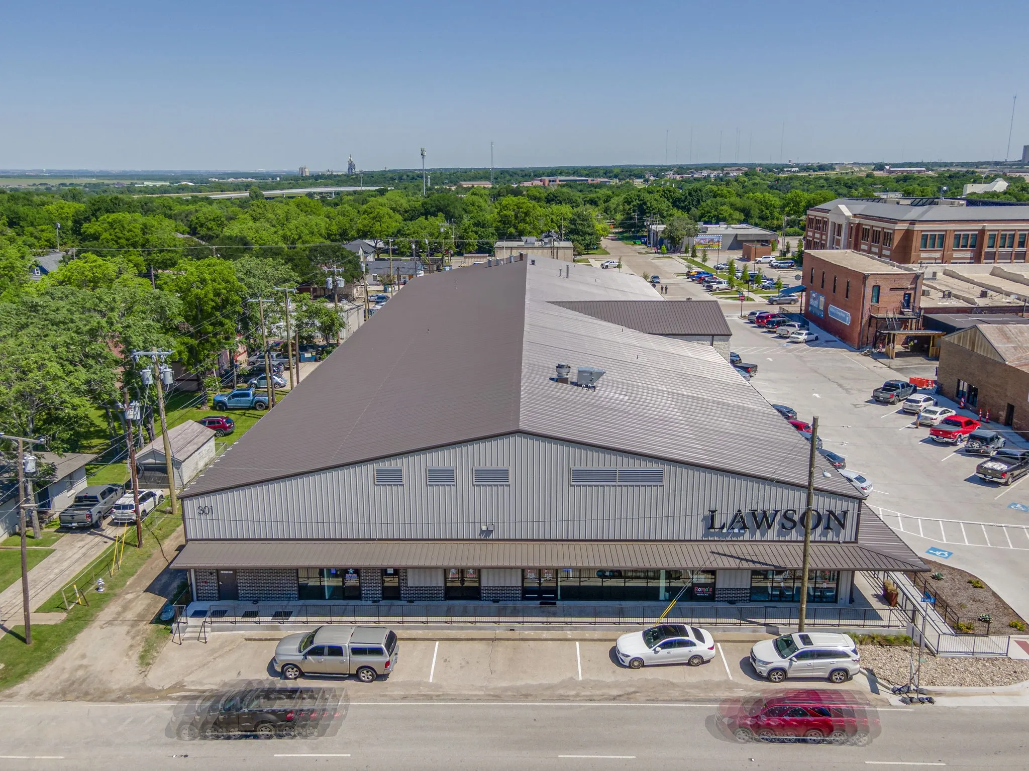 Modern commercial building featuring a metal roof, corrugated metal siding, an awning over the storefront, and ample on-site parking