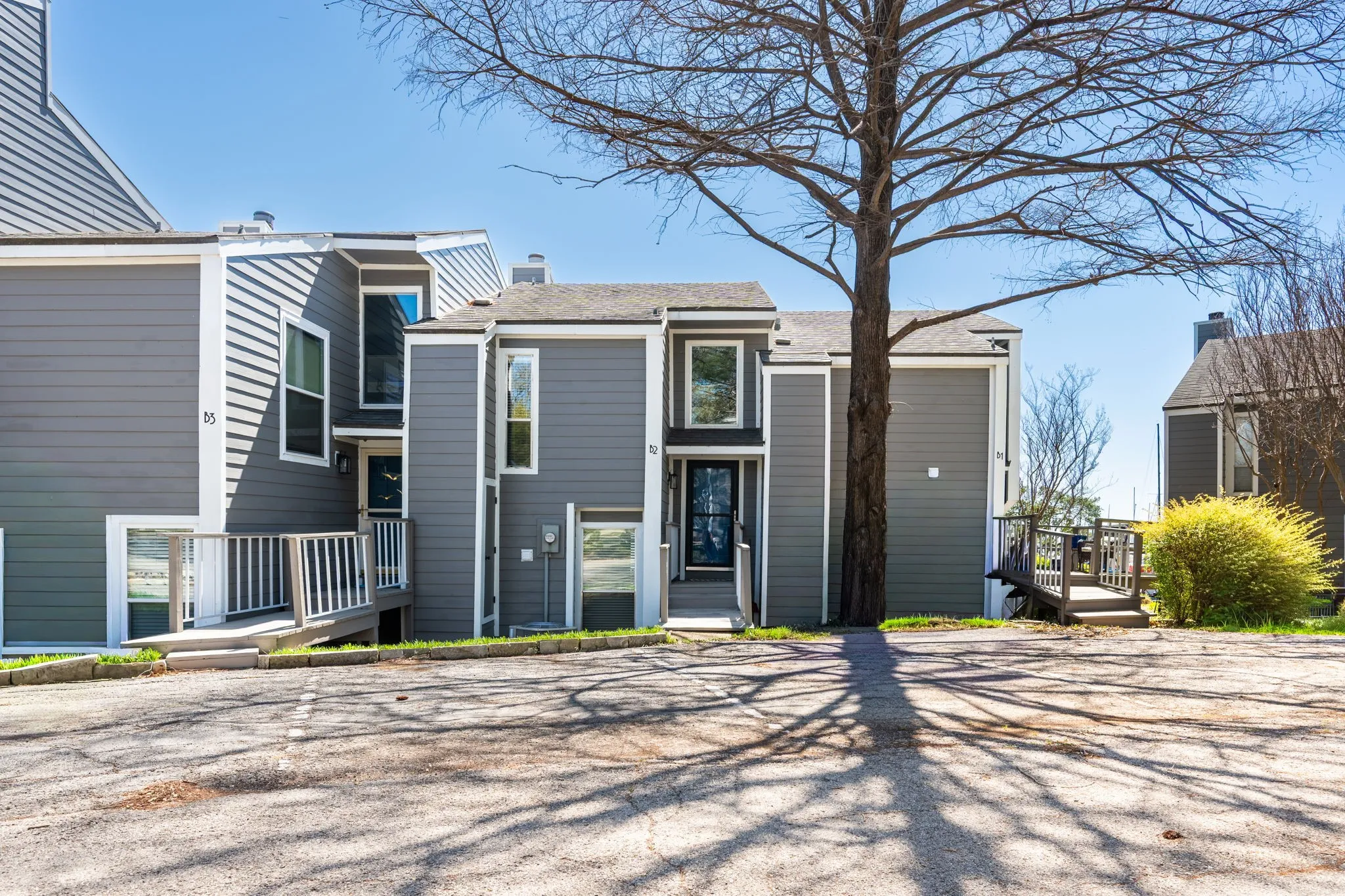 Multi-level residential exterior featuring gray horizontal siding and white trim