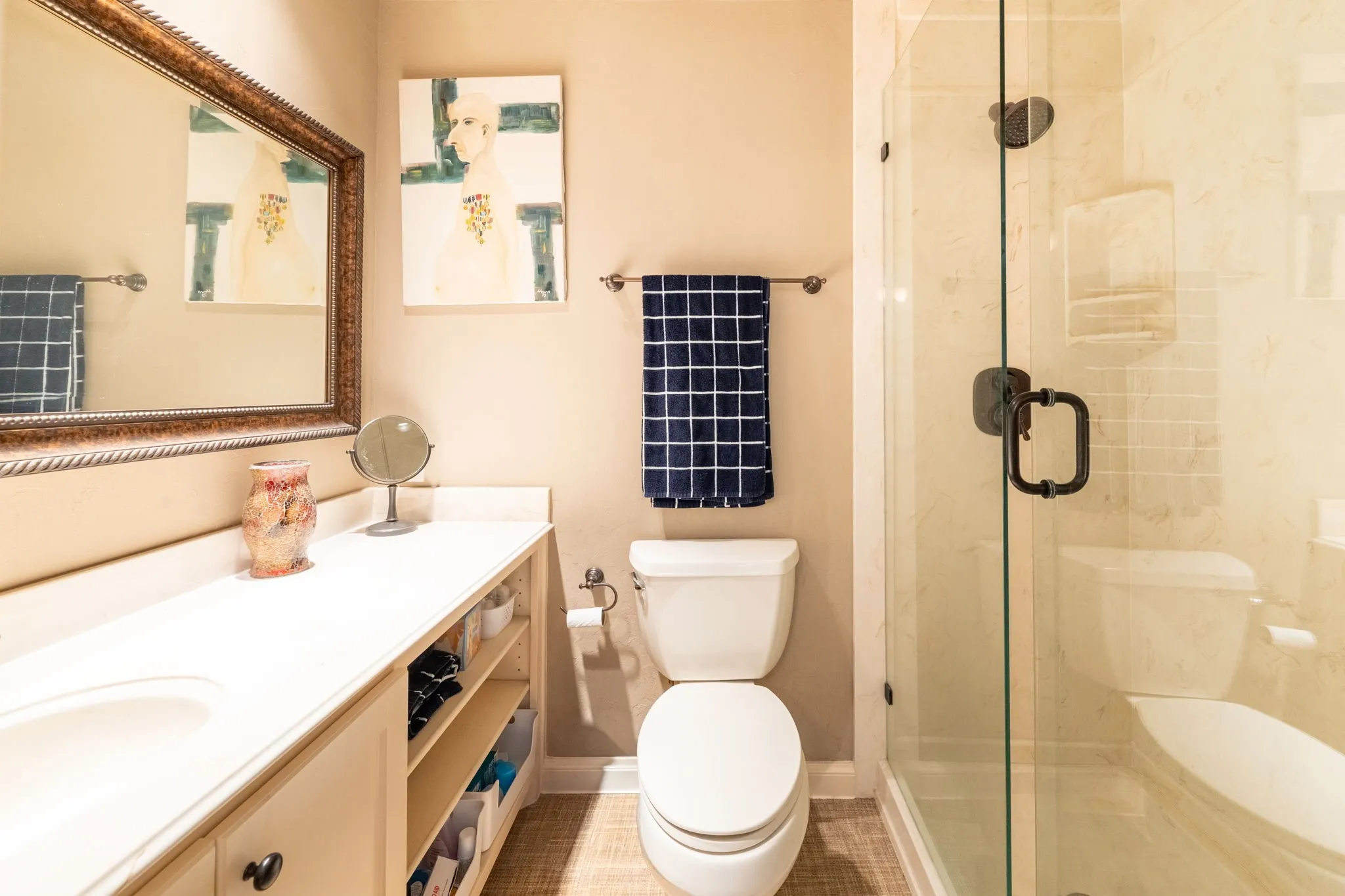 Primary bathroom featuring a glass-enclosed shower, white vanity with an integrated sink, open shelving, a framed mirror, and wood-finish flooring