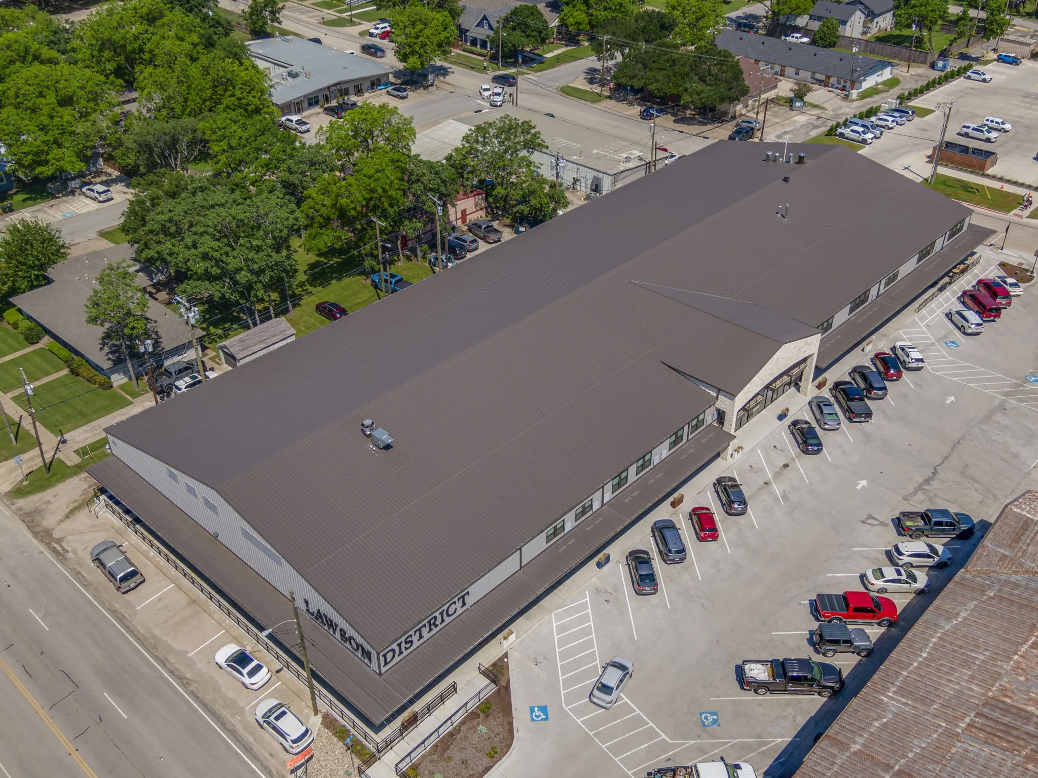 Large commercial building featuring a metal roof, extensive paved parking, and multiple storefront entries