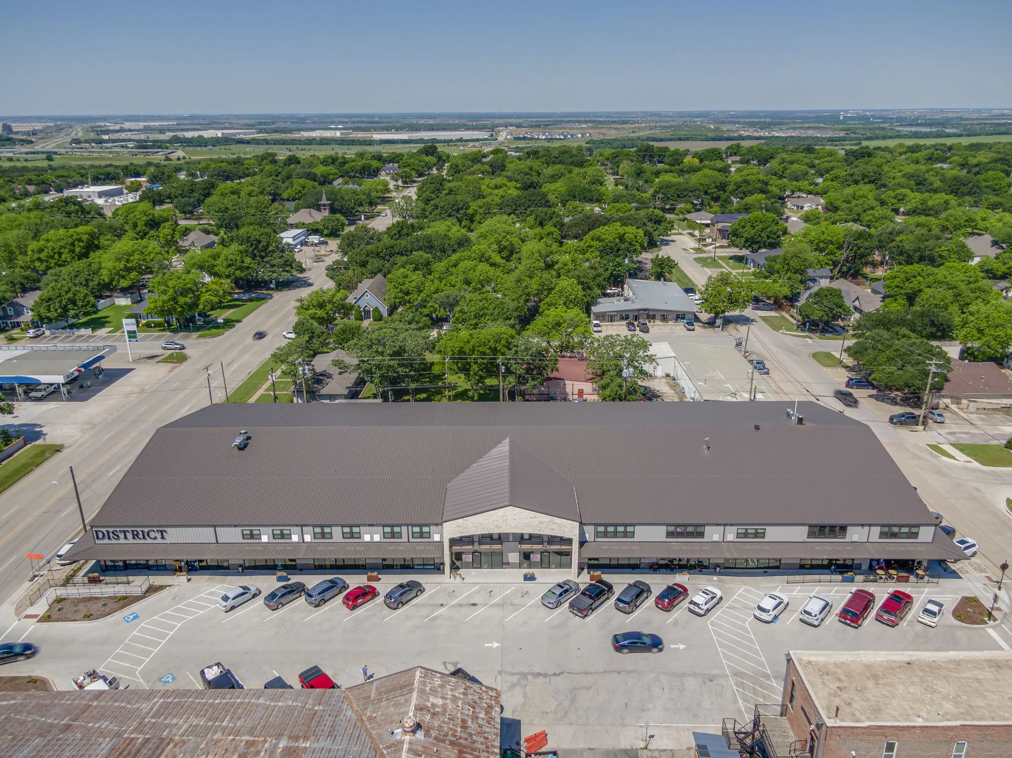 Aerial view of a commercial building with a dark gray roof and prominent "DISTRICT" signage