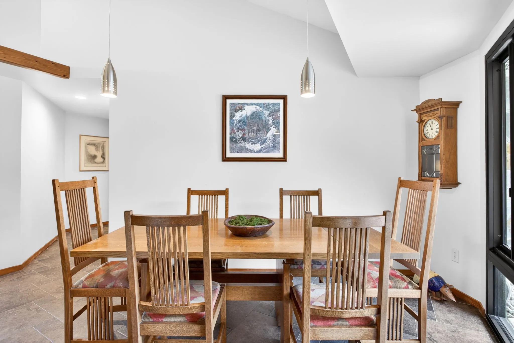 Dining space featuring vaulted ceilings, two pendant light fixtures, and tiled flooring