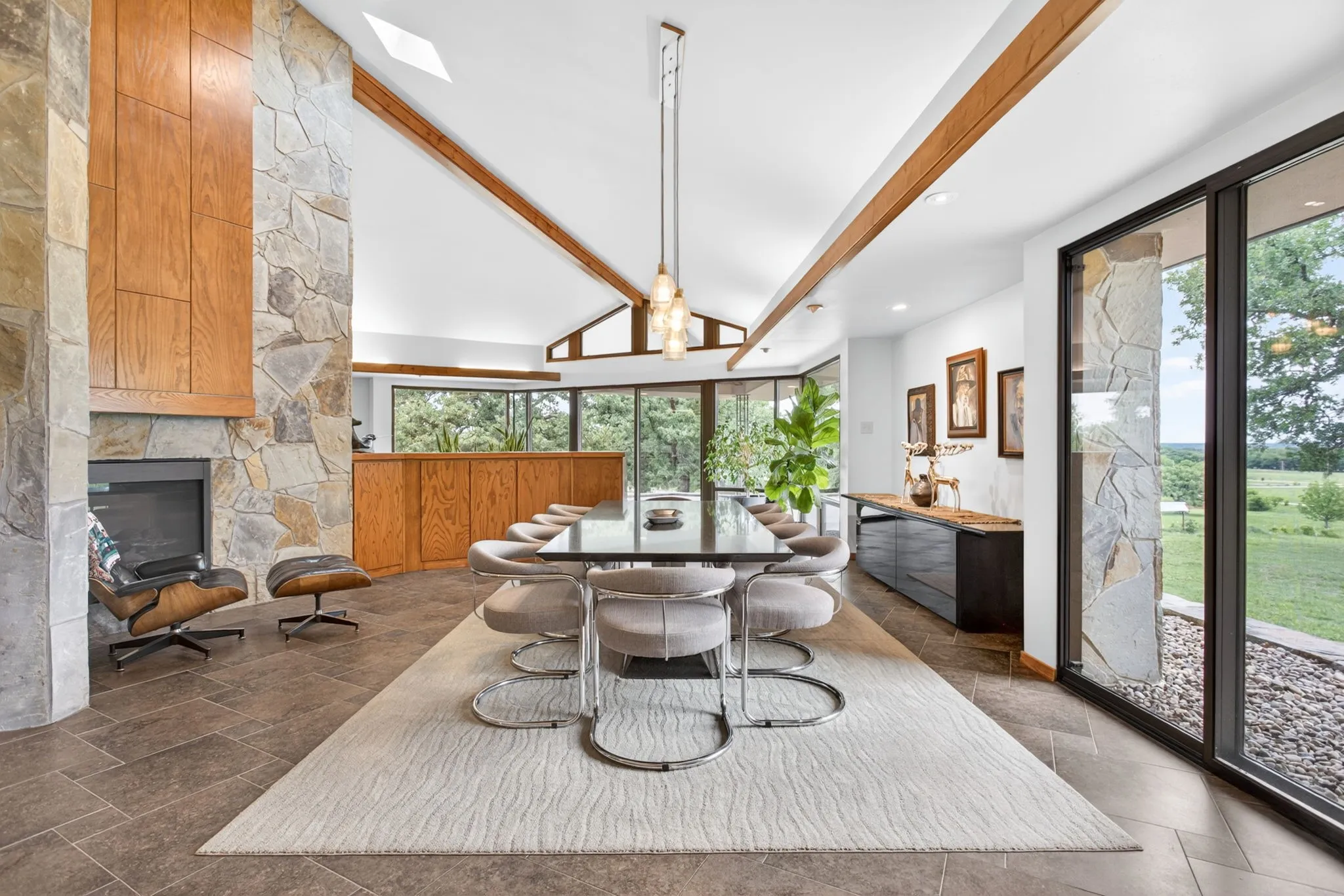 Spacious interior featuring a vaulted ceiling with exposed wood beams, extensive natural stone wall accents, and large format tile flooring