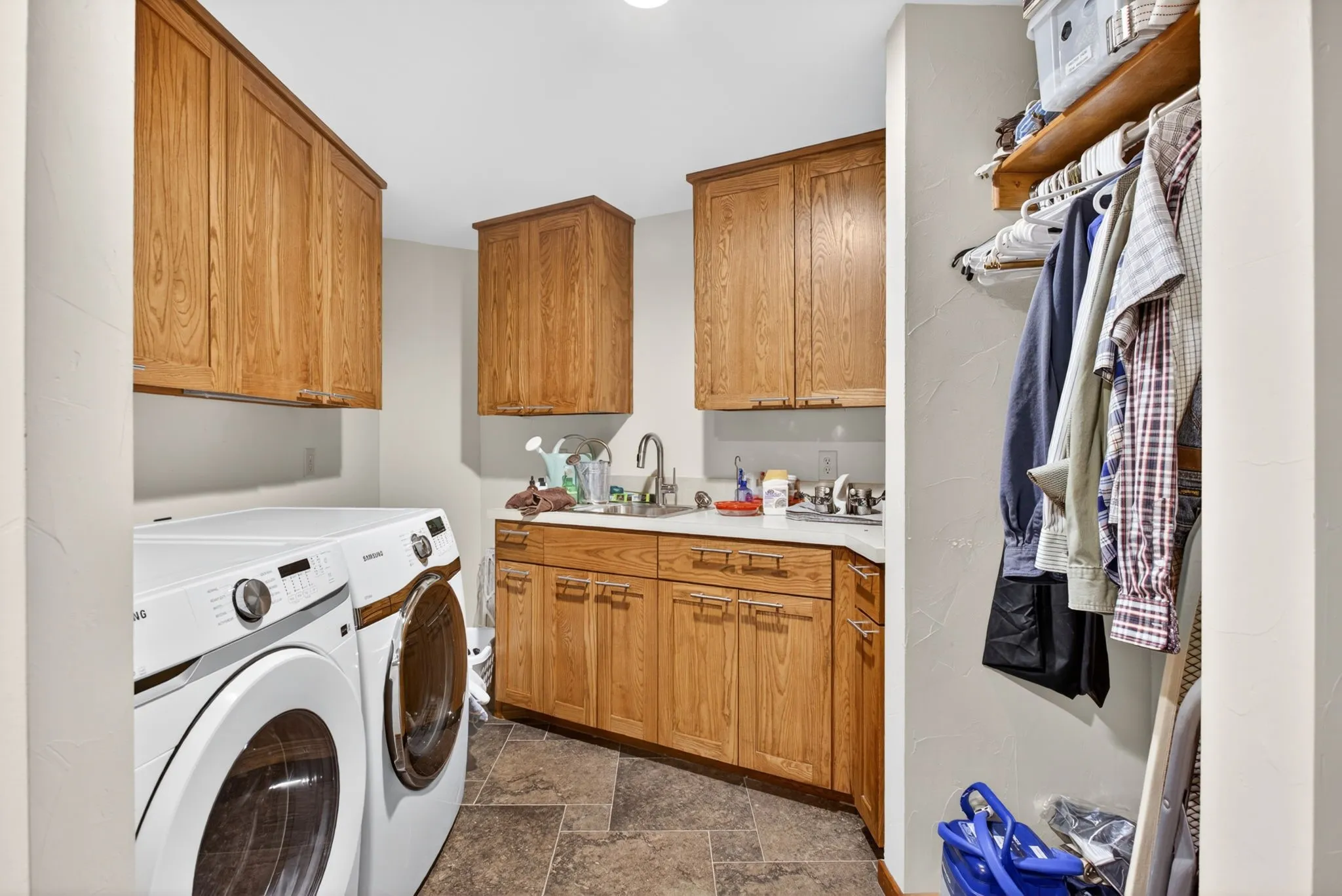 Utility room featuring a built-in sink with a countertop, wood cabinetry, and tiled flooring