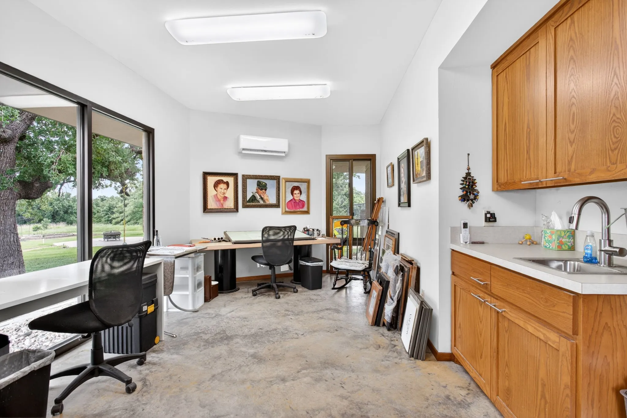 Art Studio - Spacious room featuring concrete flooring, a wall of windows, and an integrated wet bar with wood-finish cabinetry and a stainless steel sink