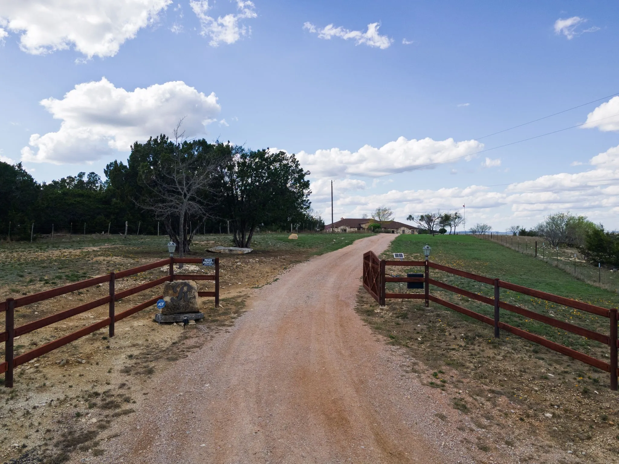 Gated gravel driveway extending toward a single-story residence