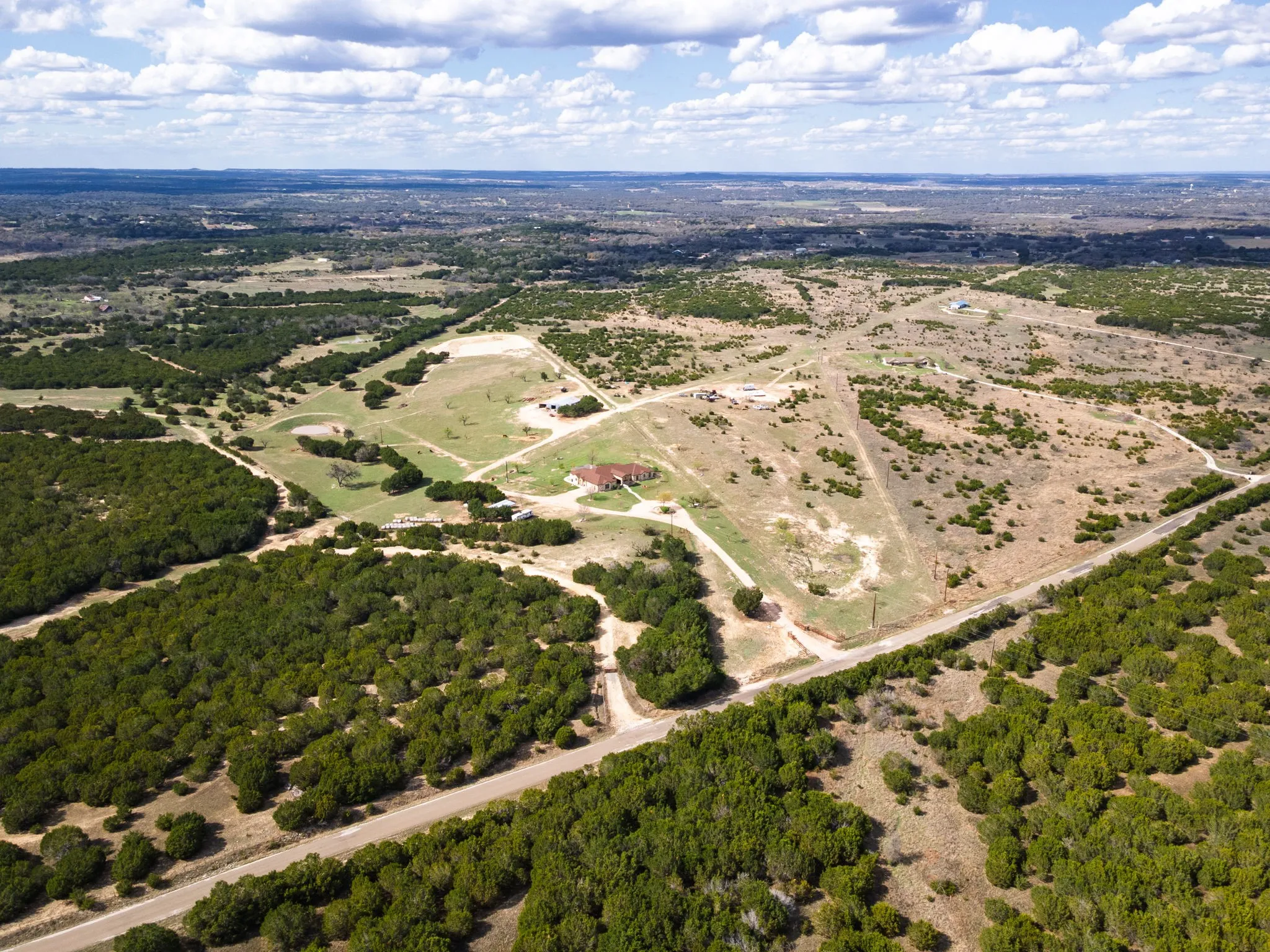 Expansive property featuring a central residence, surrounding open land, and wooded sections