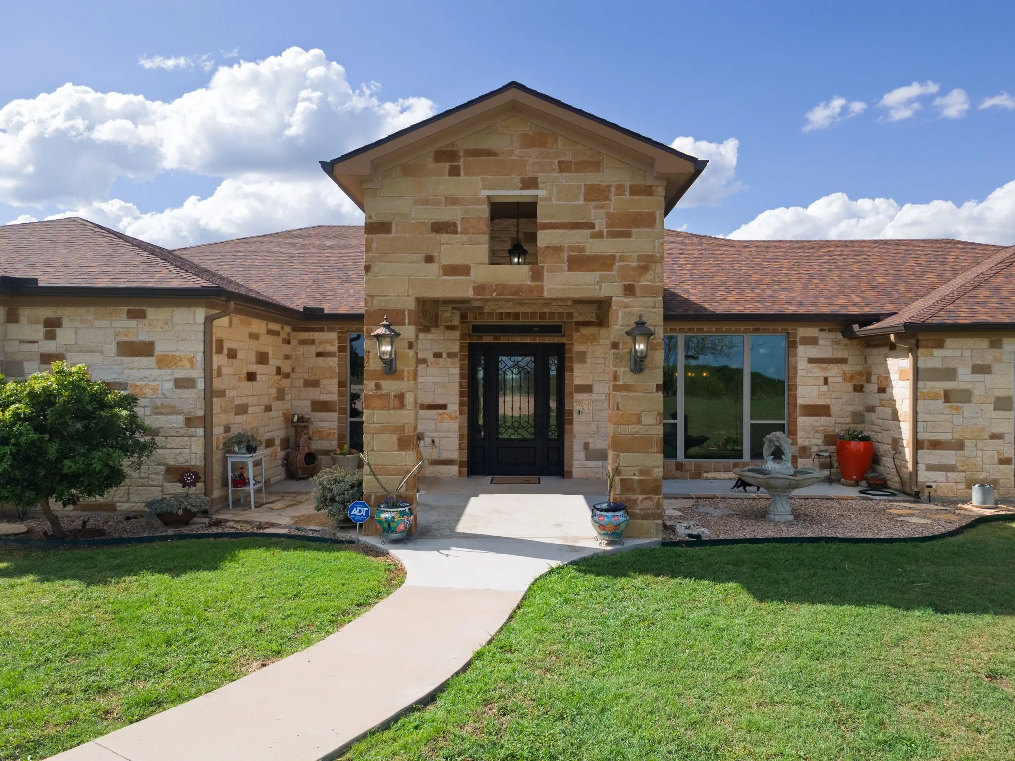 Stone facade residence featuring a prominent entryway with an arched roofline