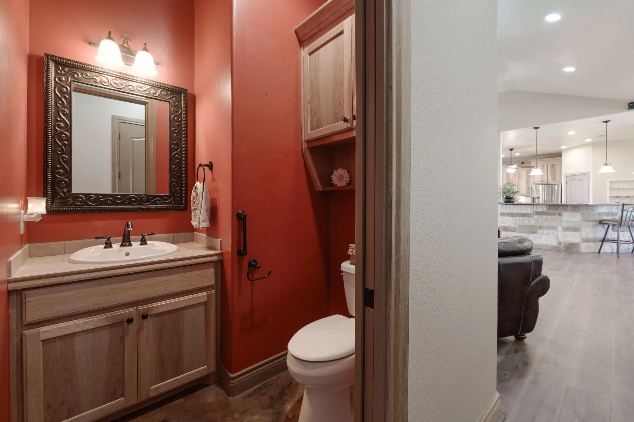 Powder room featuring a single vanity with a white oval sink, an ornate framed mirror, and a wood-finish cabinet