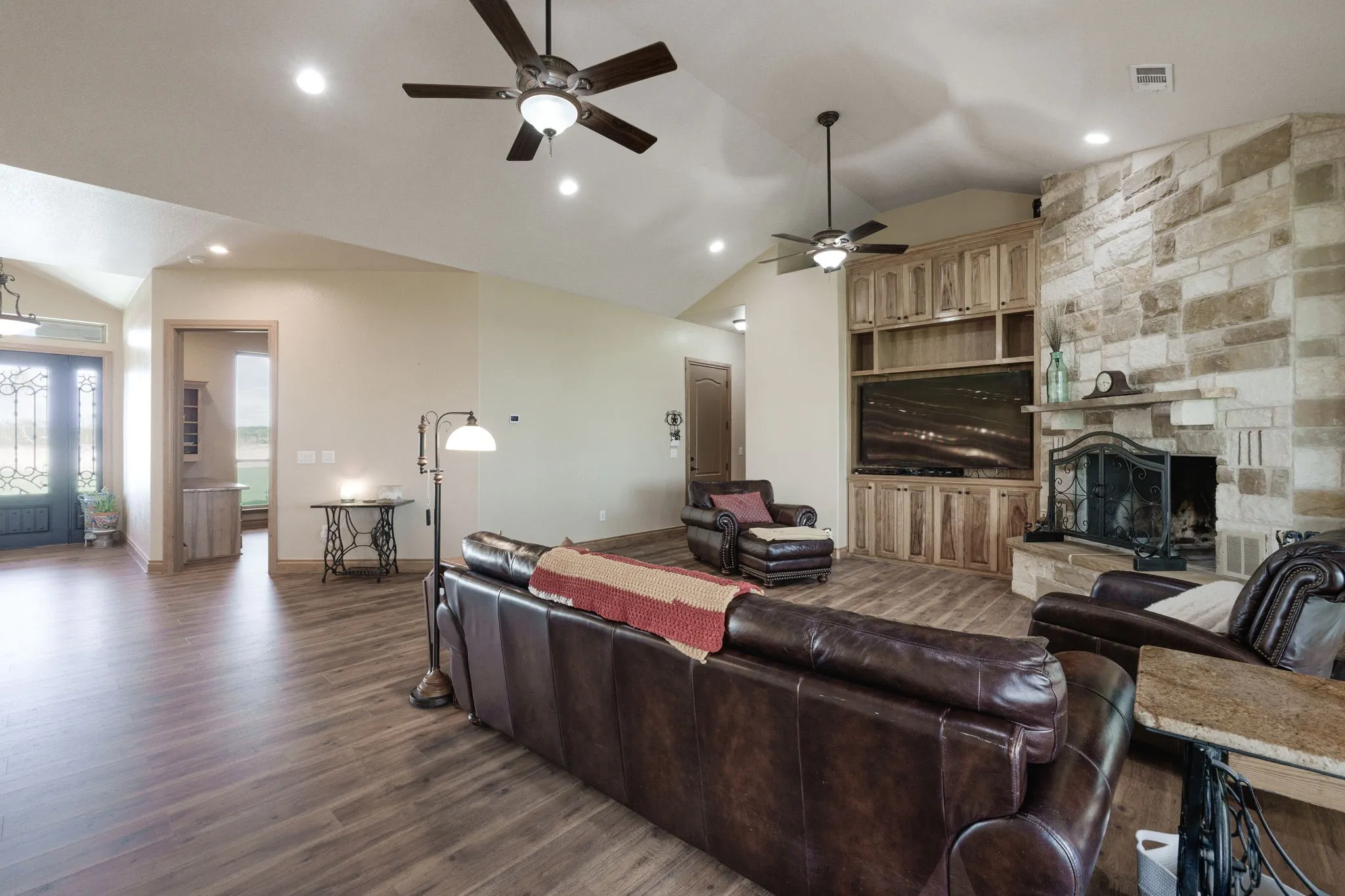 Spacious living area featuring wood-finish flooring, a stone-clad fireplace, and built-in wood cabinetry