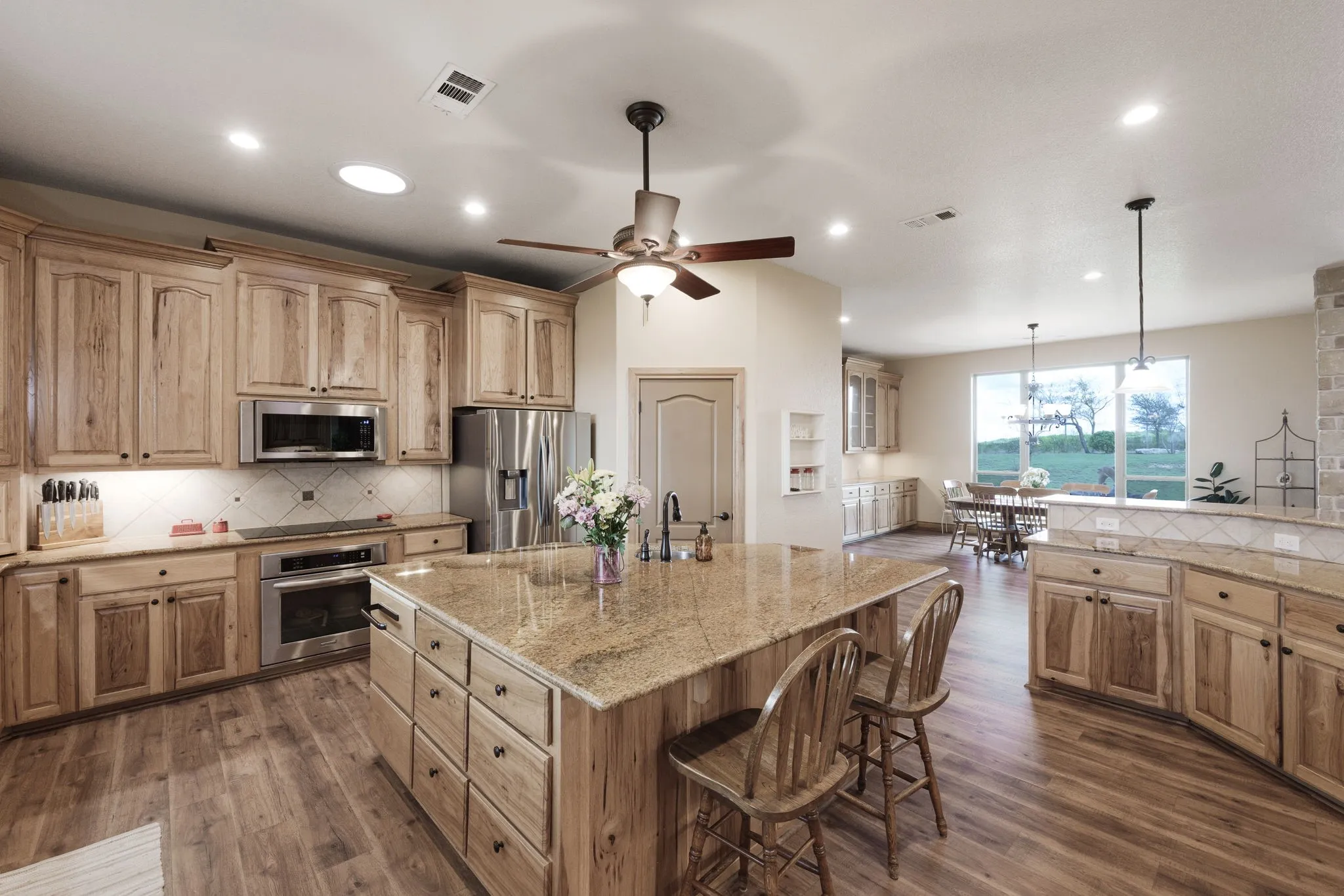 Expansive kitchen featuring light wood cabinetry, a large center island with a stone countertop, and stainless steel appliances