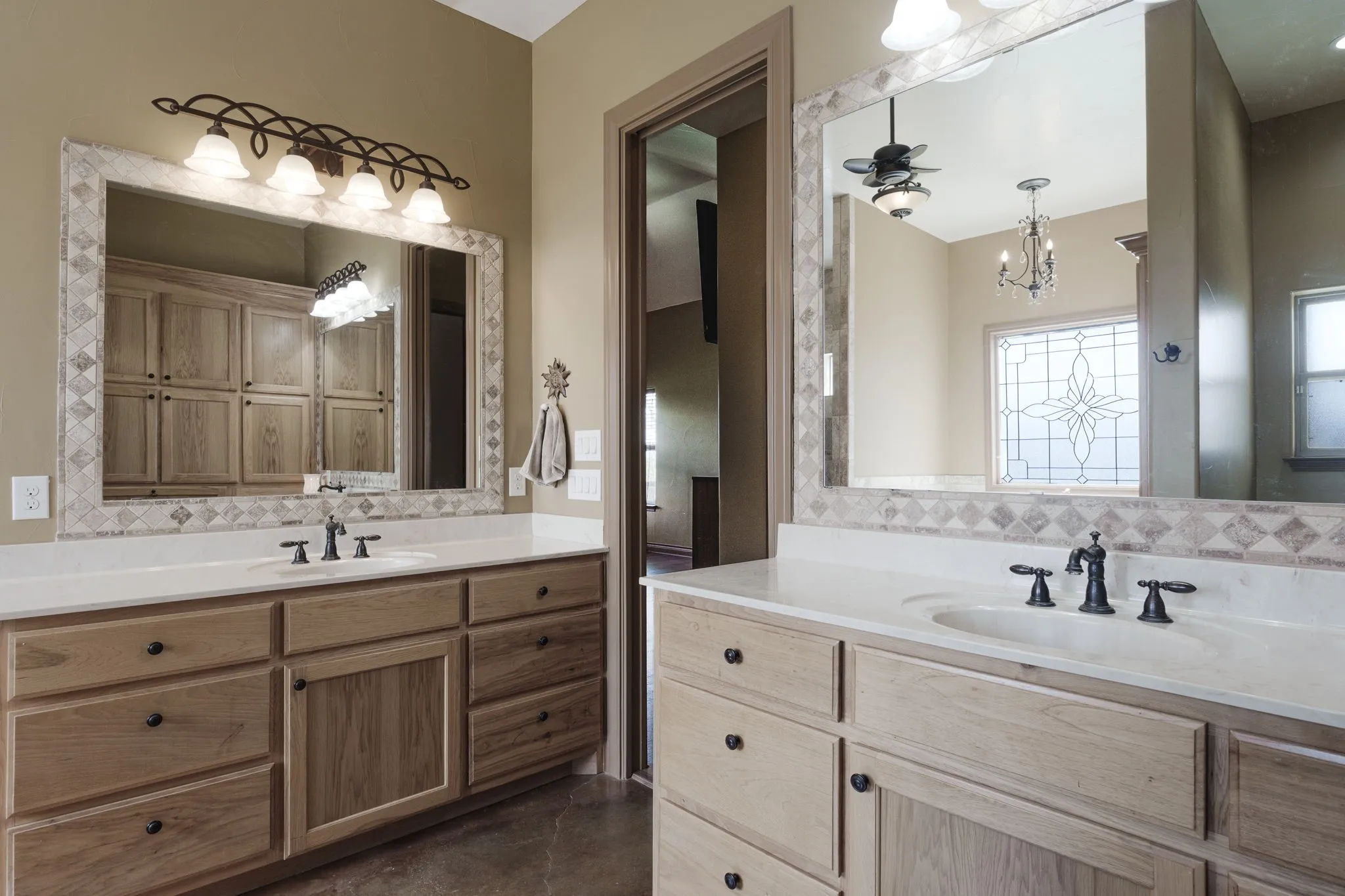Dual vanities featuring light wood-finish cabinetry, white countertops, and black hardware