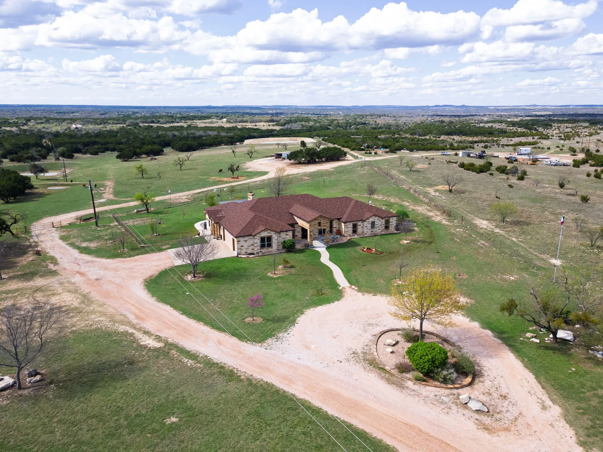 Sprawling ranch-style home featuring a stone facade and a brown shingle roof