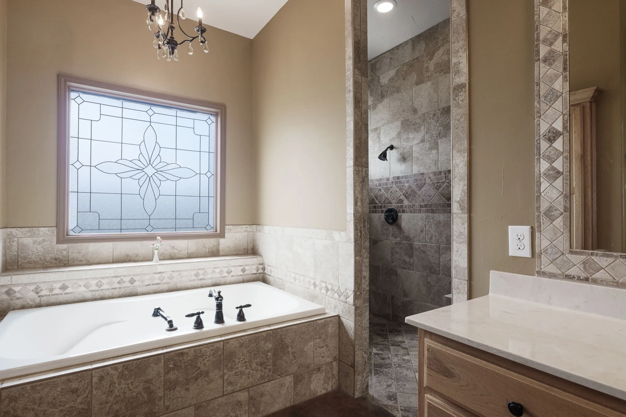 Bathroom featuring a built-in tub with matte black fixtures, a decorative privacy window, and a tiled shower with contrasting accent tile