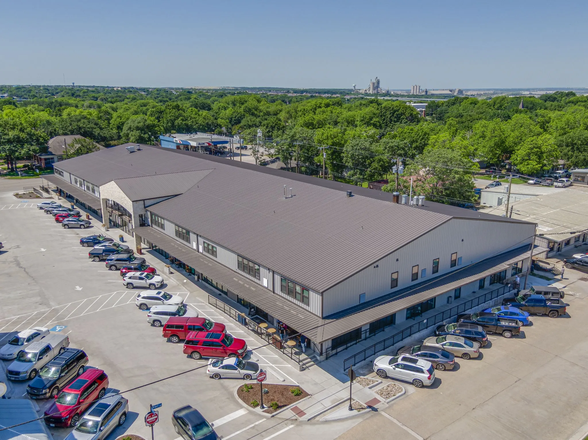 Expansive commercial building featuring a metal roof, light gray siding, and stone facade accents