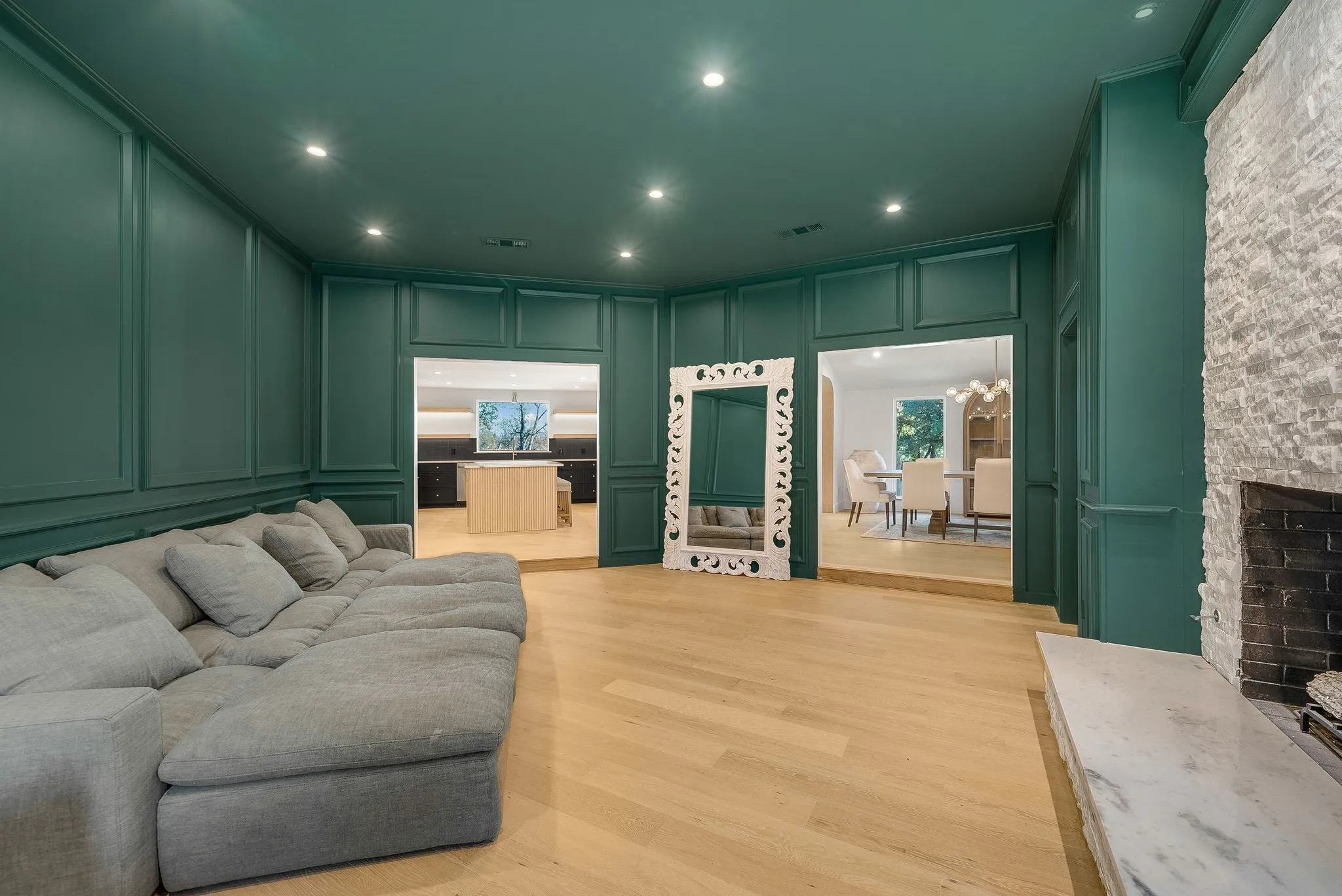 Living area featuring a decorative wall, a stone fireplace, light wood-style flooring, recessed lighting, and a chandelier