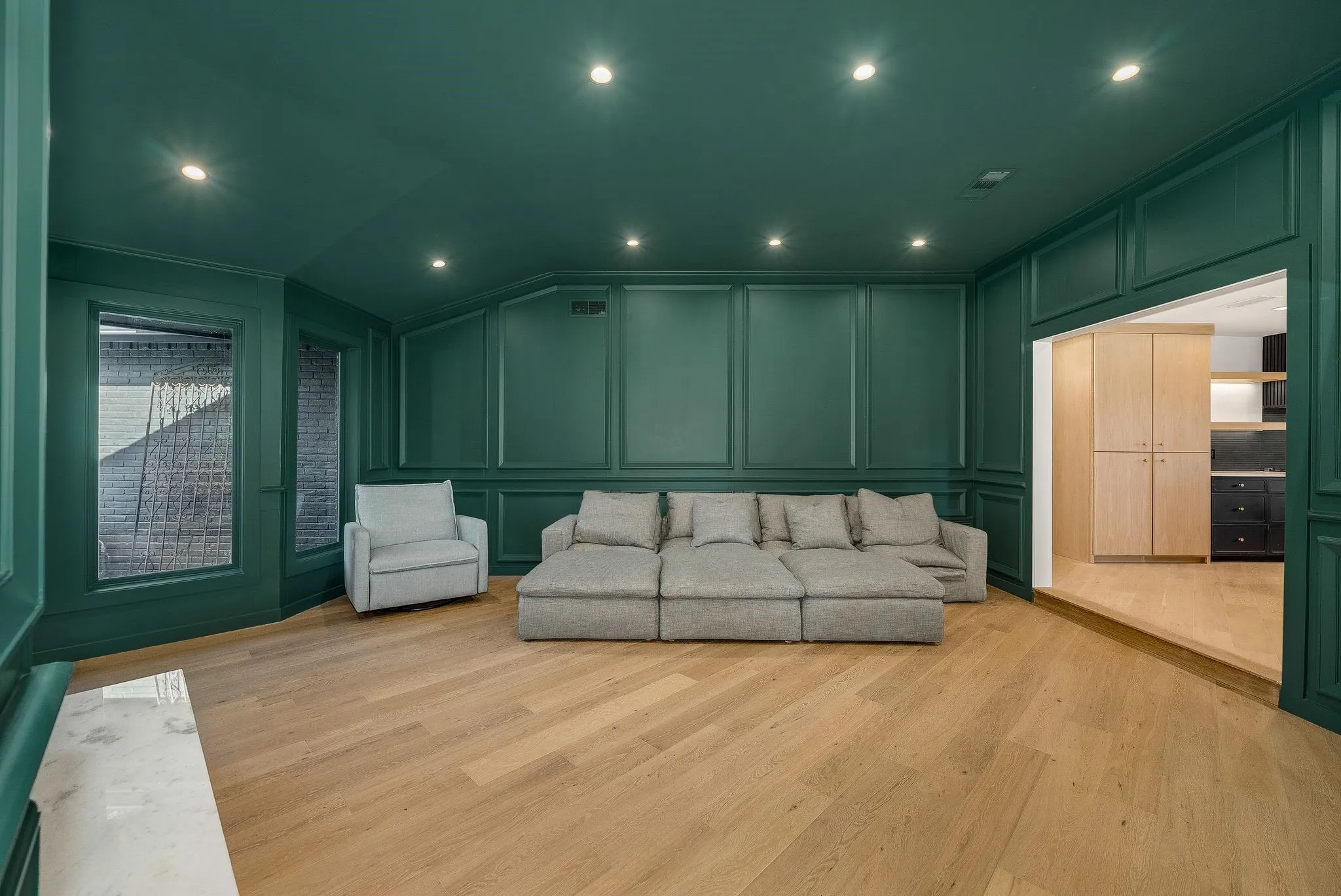 Living room featuring a decorative wall, vaulted ceiling, light wood-type flooring, and recessed lighting