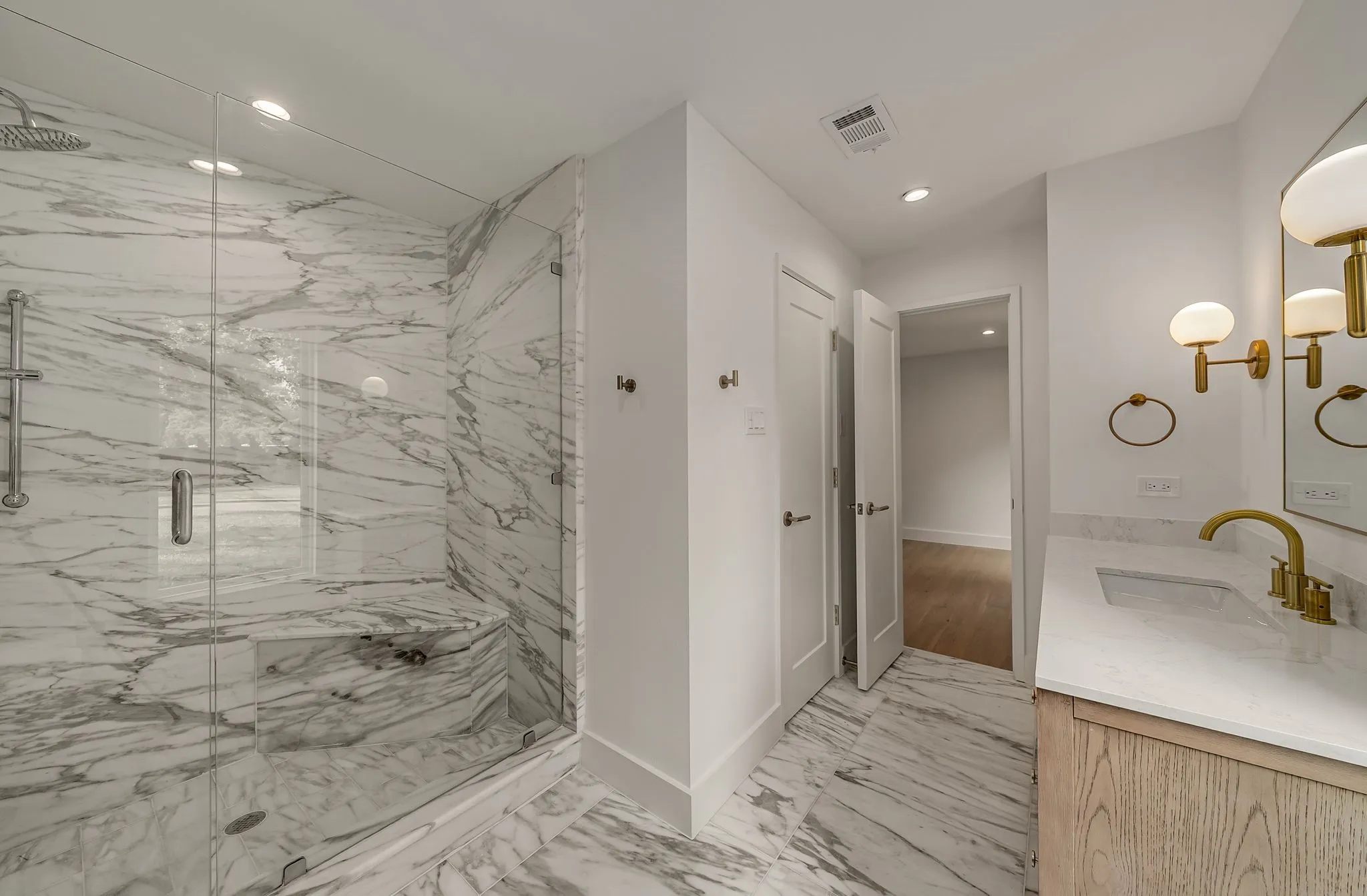 Full bath featuring vanity, a marble finish shower, light marble finish flooring, and recessed lighting