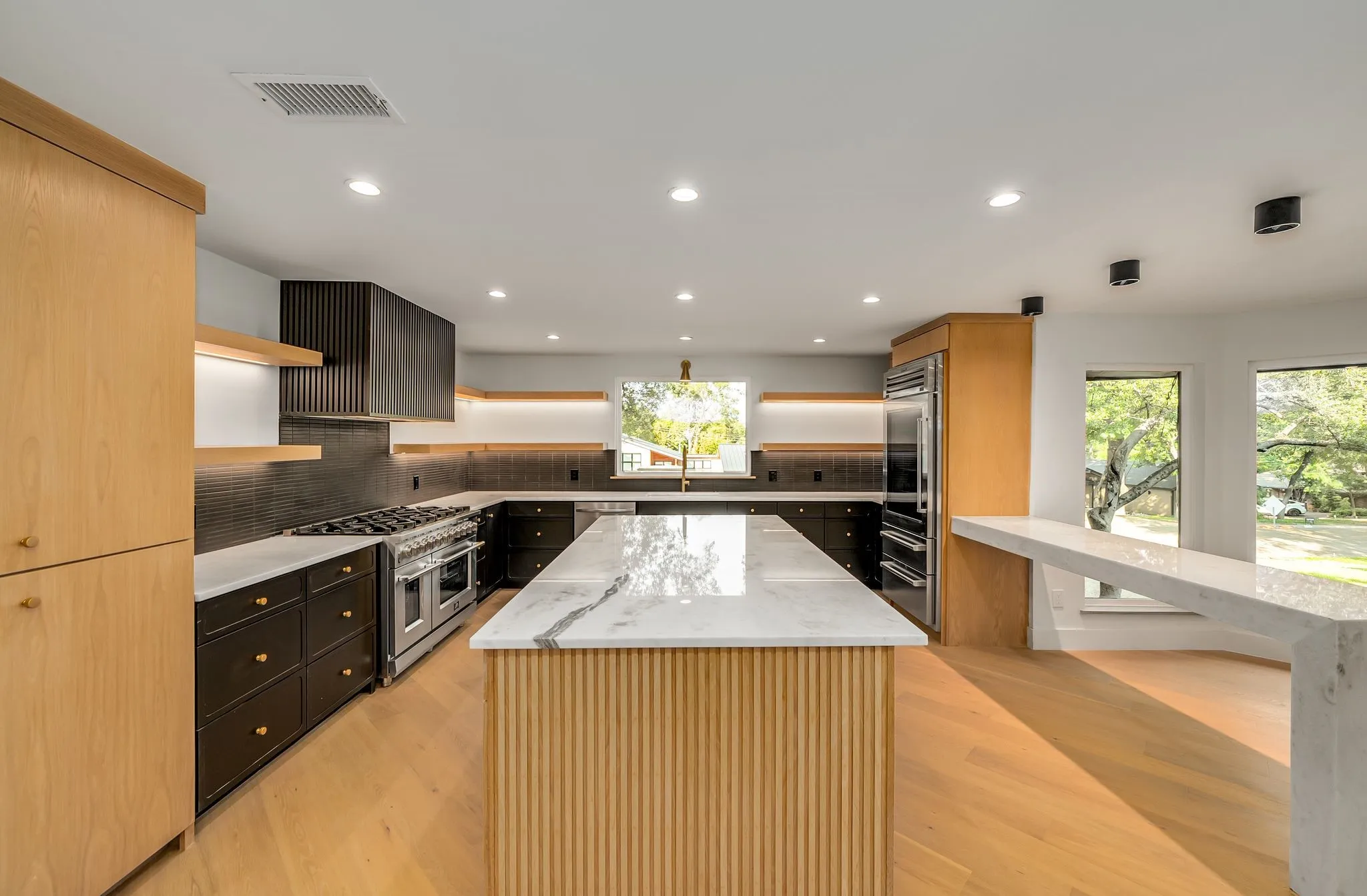 Kitchen featuring light stone countertops, open shelves, decorative backsplash, light wood-style flooring, and recessed lighting