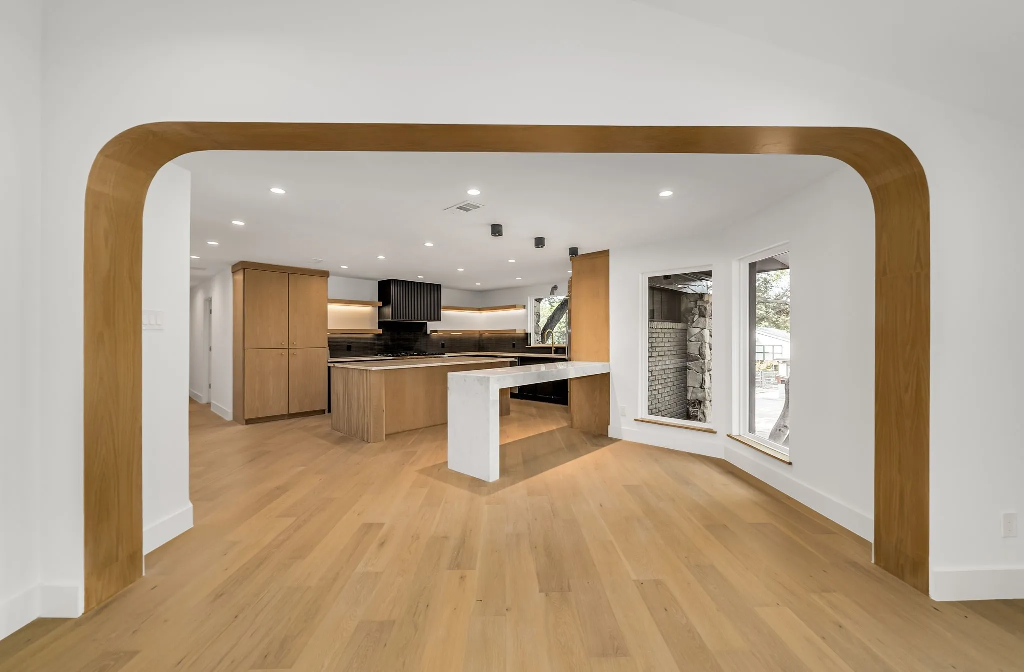 Kitchen with arched walkways, modern cabinets, recessed lighting, light wood-type flooring, and a breakfast bar