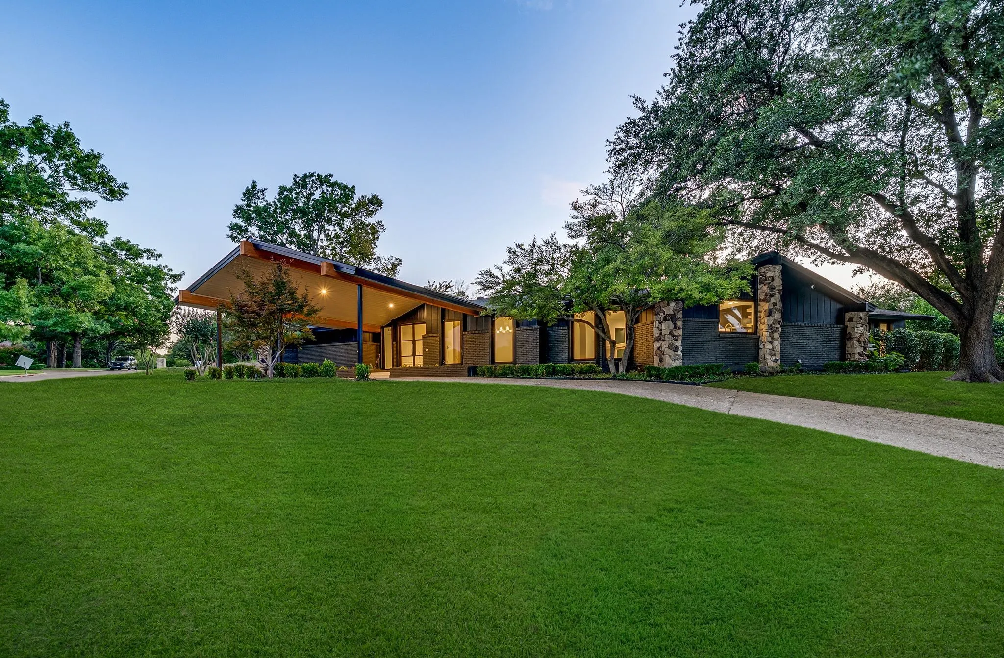 Mid-century home featuring a front lawn, driveway, and stone siding