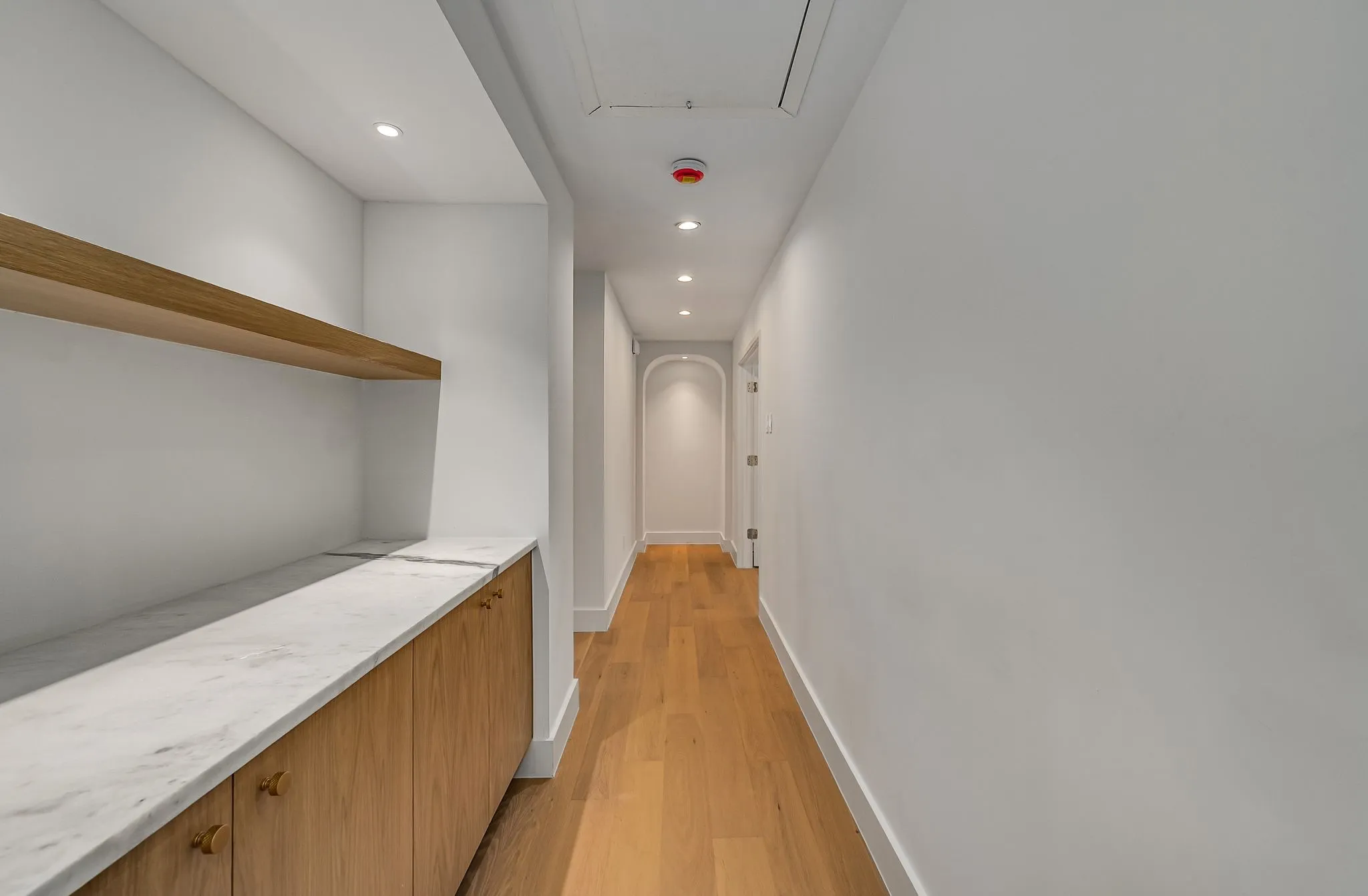 Hall featuring light wood-style floors, recessed lighting, and arched walkways