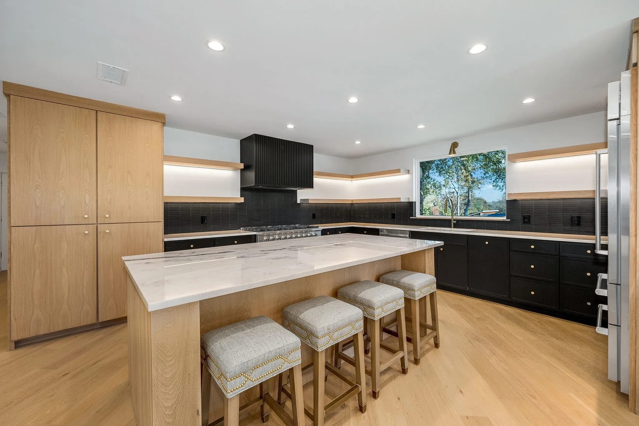 Kitchen with a breakfast bar, light stone countertops, a kitchen island, dark cabinets, and light wood-type flooring