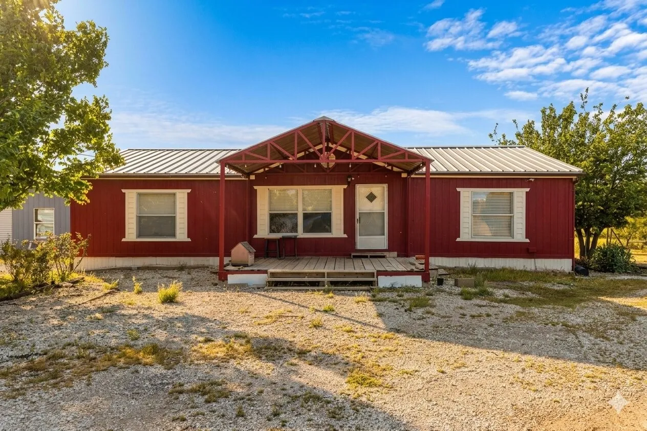Red exterior siding with white trim, covered front porch, and metal roofing