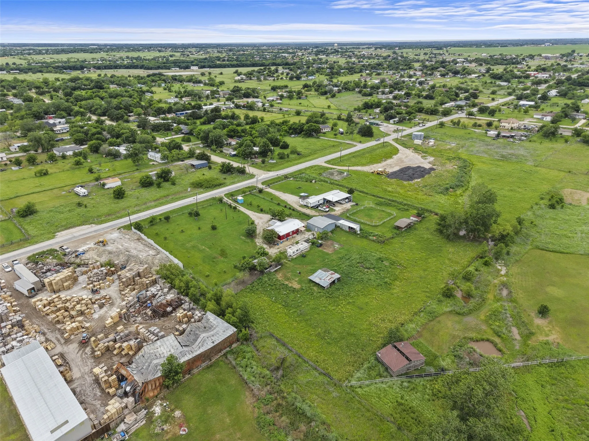 Aerial depiction of a broad land area featuring scattered residential structures and agricultural land