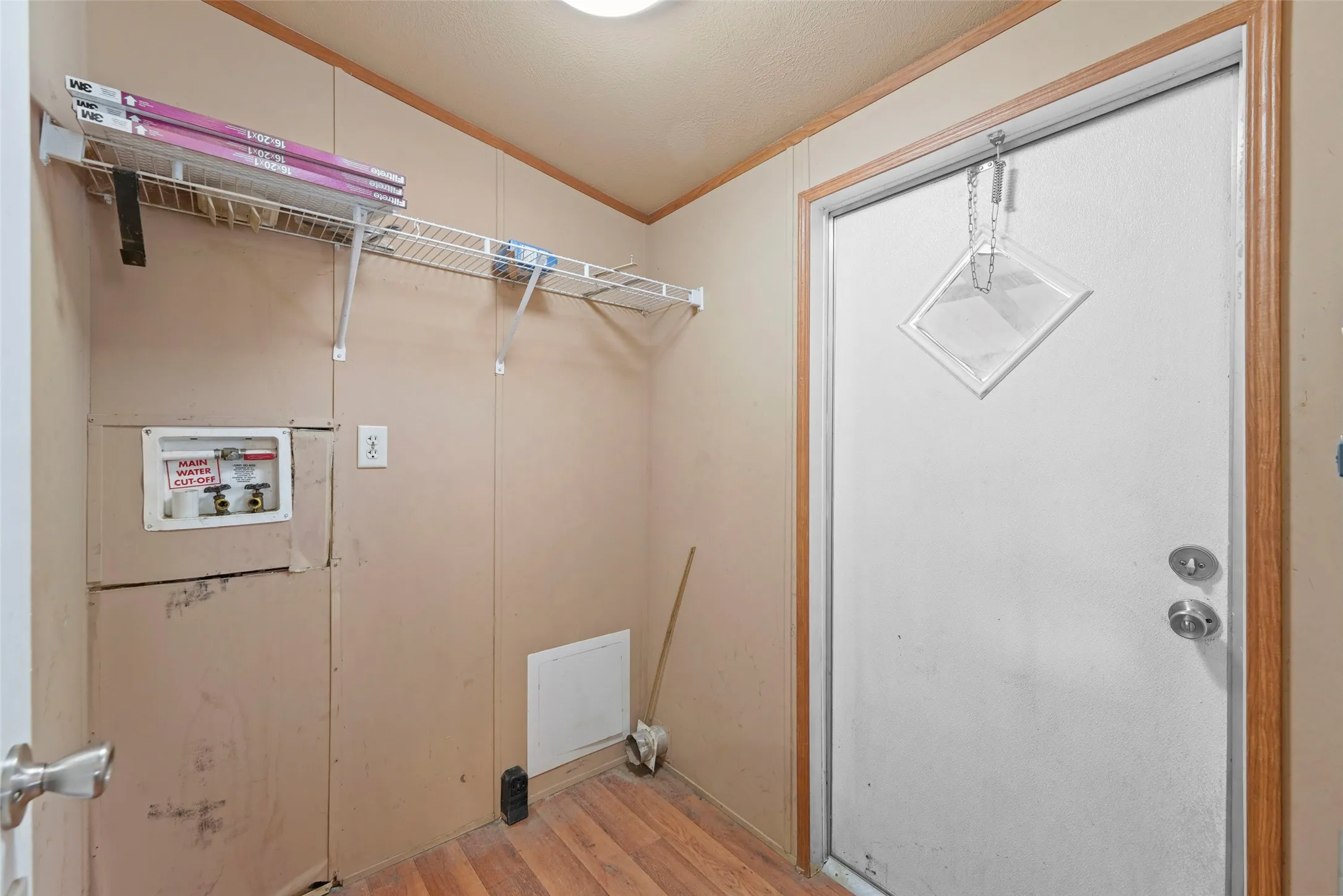 Utility area featuring wood-finish flooring and a white paneled door with a diamond-shaped window