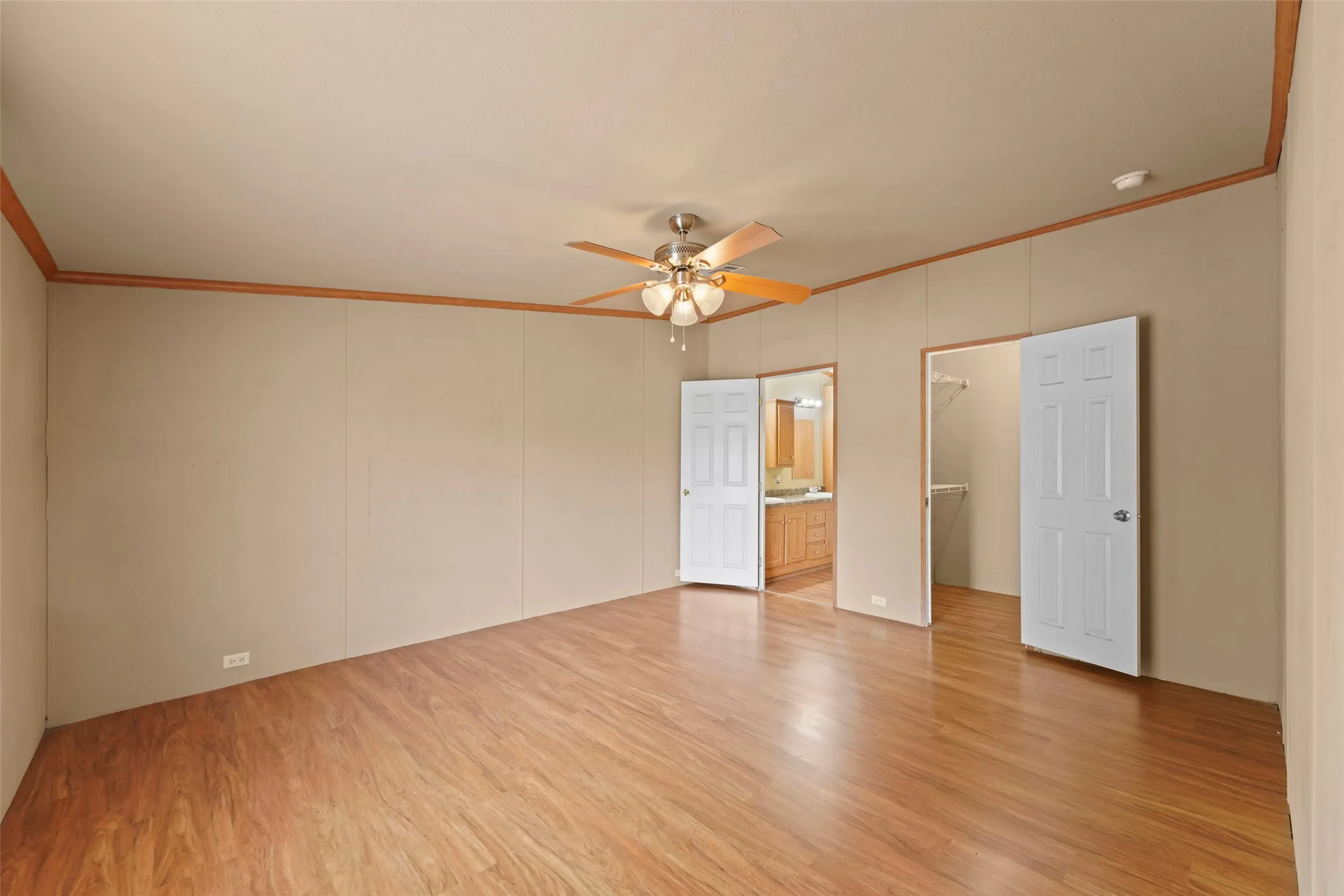 Spacious room featuring wood-finish flooring and a ceiling fan with integrated lighting
