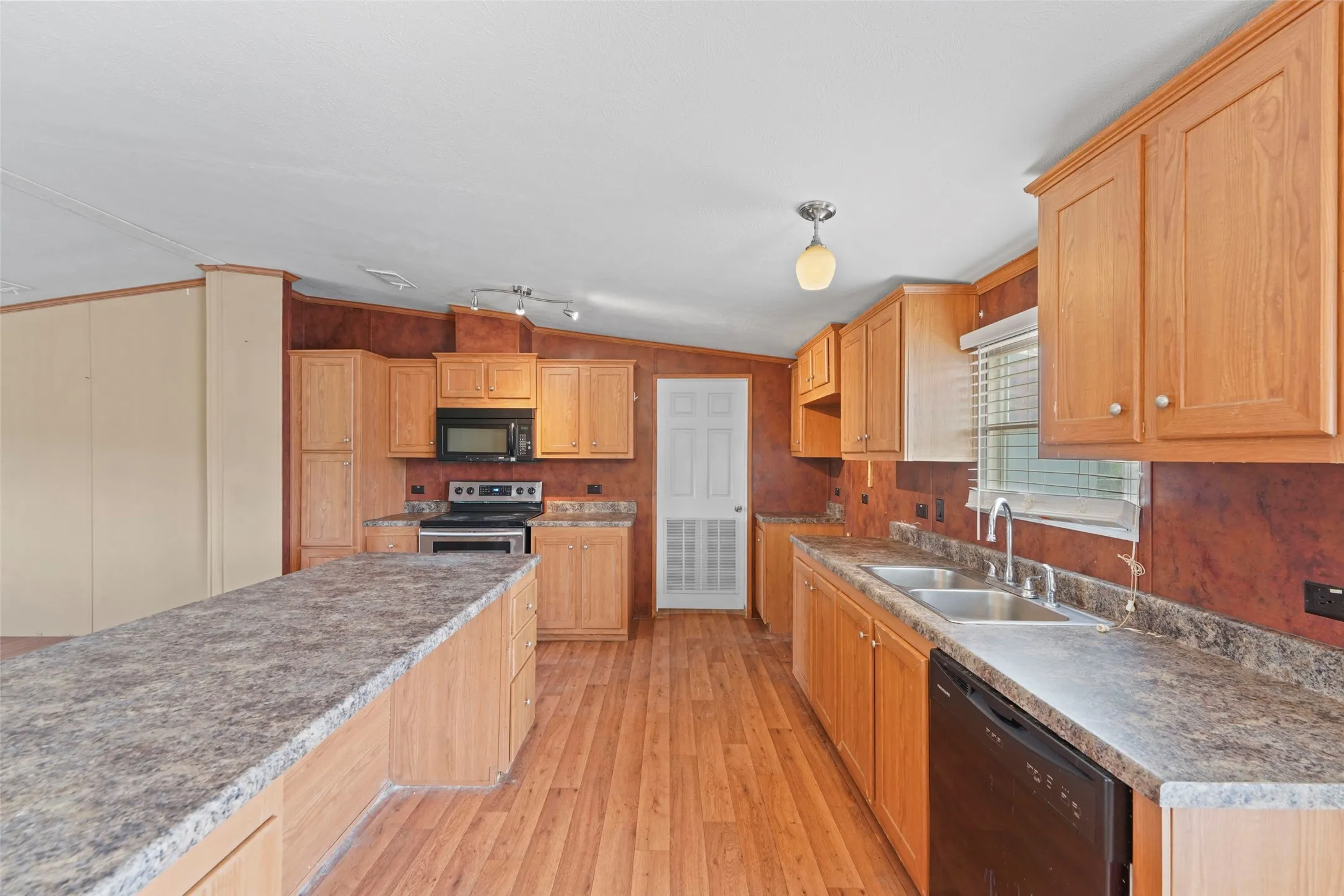 Kitchen featuring wood-finish flooring, a double basin stainless steel sink, black range, black microwave, and black dishwasher